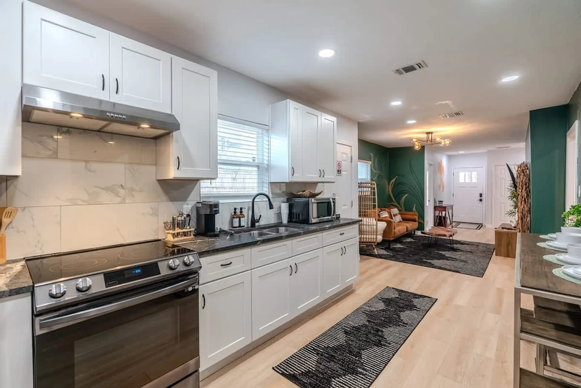Kitchen with white cabinets, stainless steel appliances, and open living area.