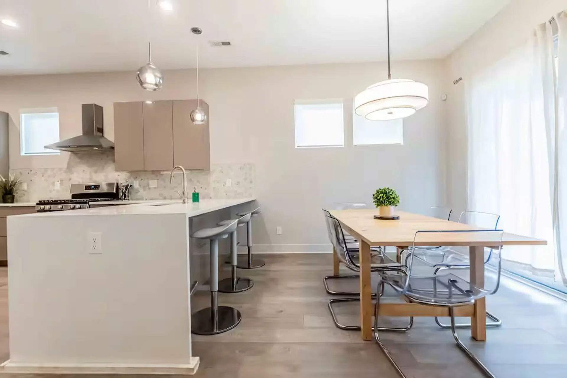 Kitchen island with bar stools and a dining table with chairs.