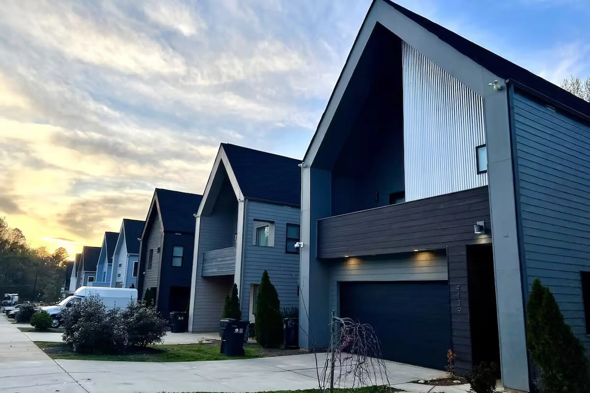 Modern townhouses with striking architectural features, under a cloudy sky.