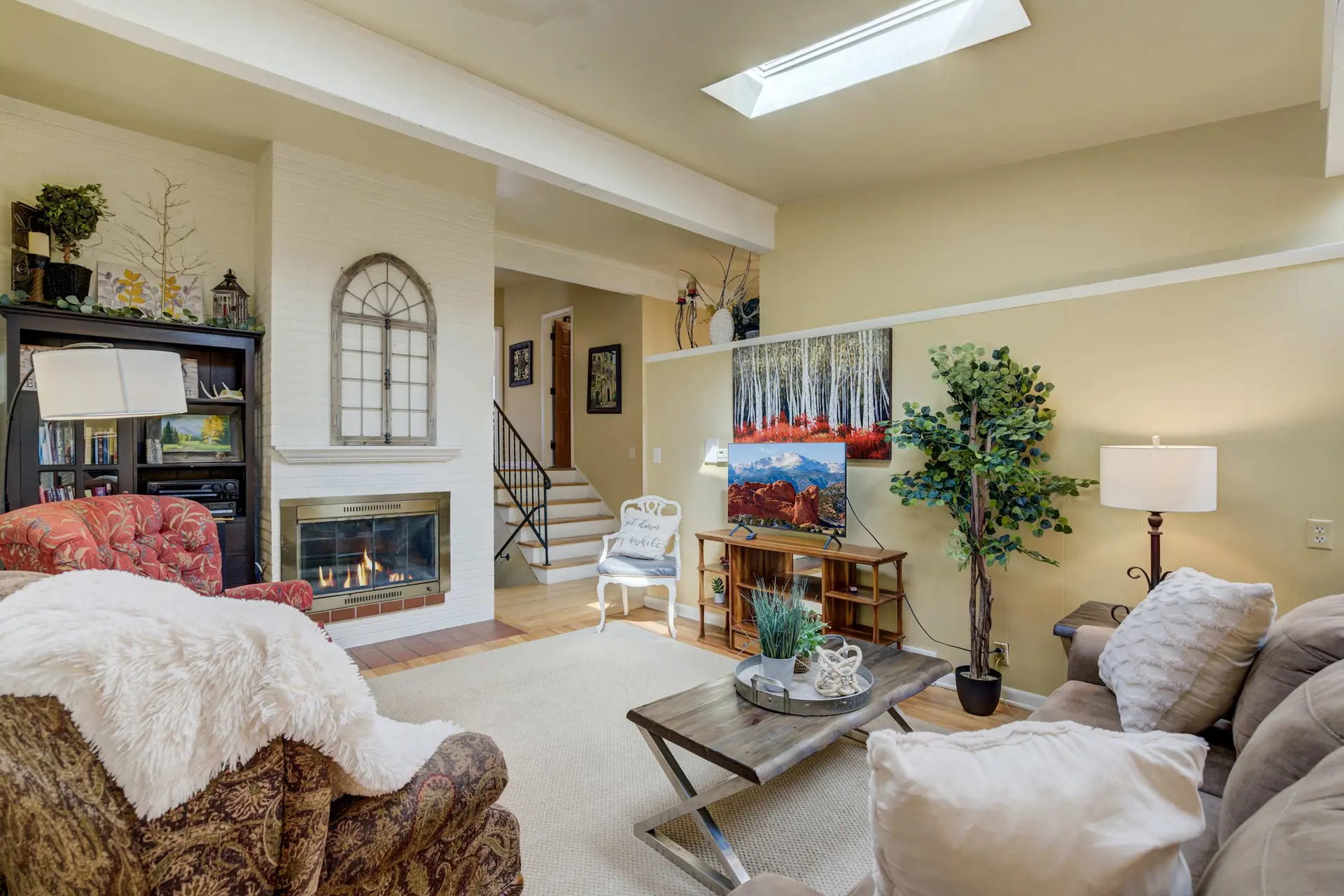A living room with a fireplace, television, couch, and chairs.