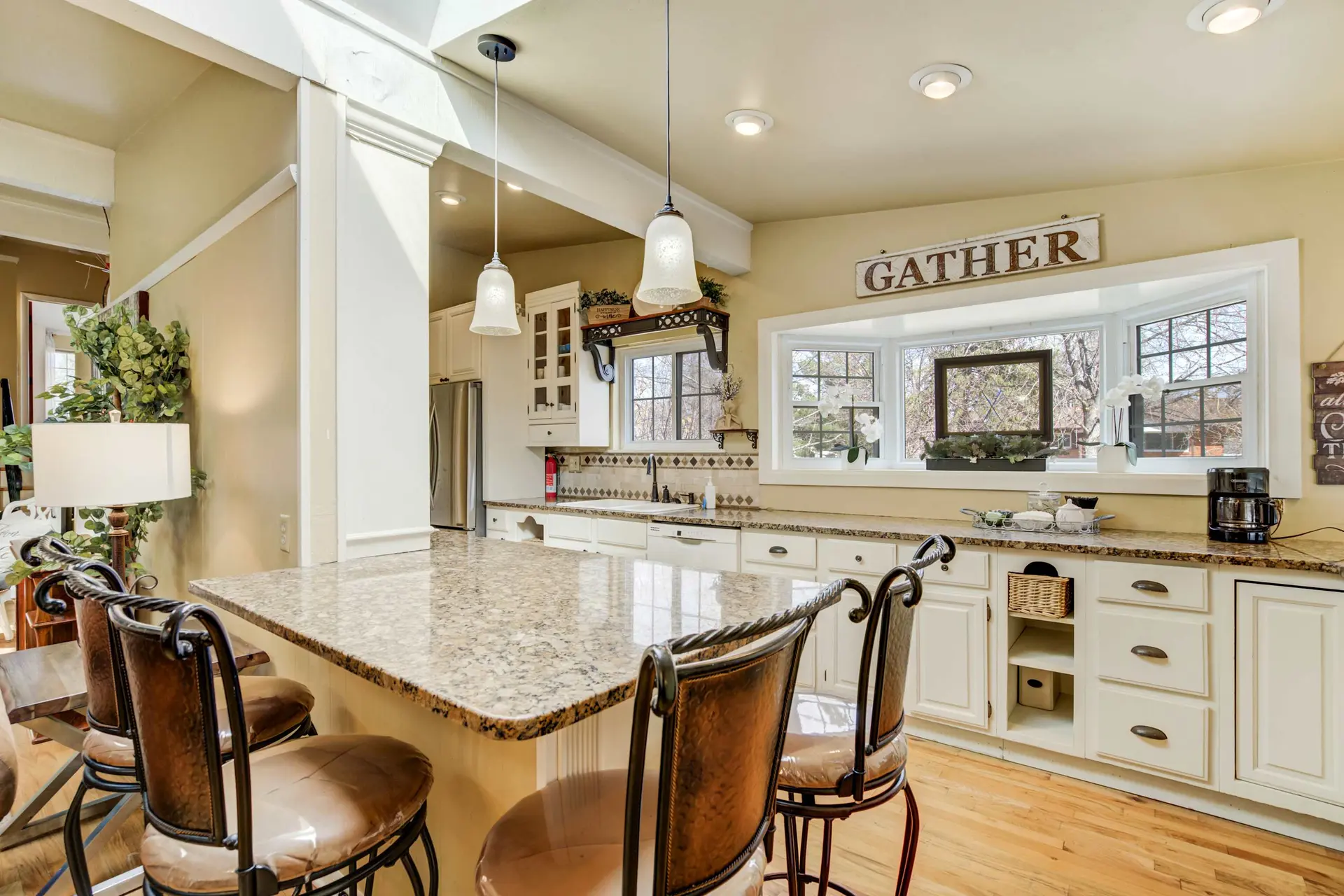 A bright, traditional kitchen with granite countertops and white cabinetry.