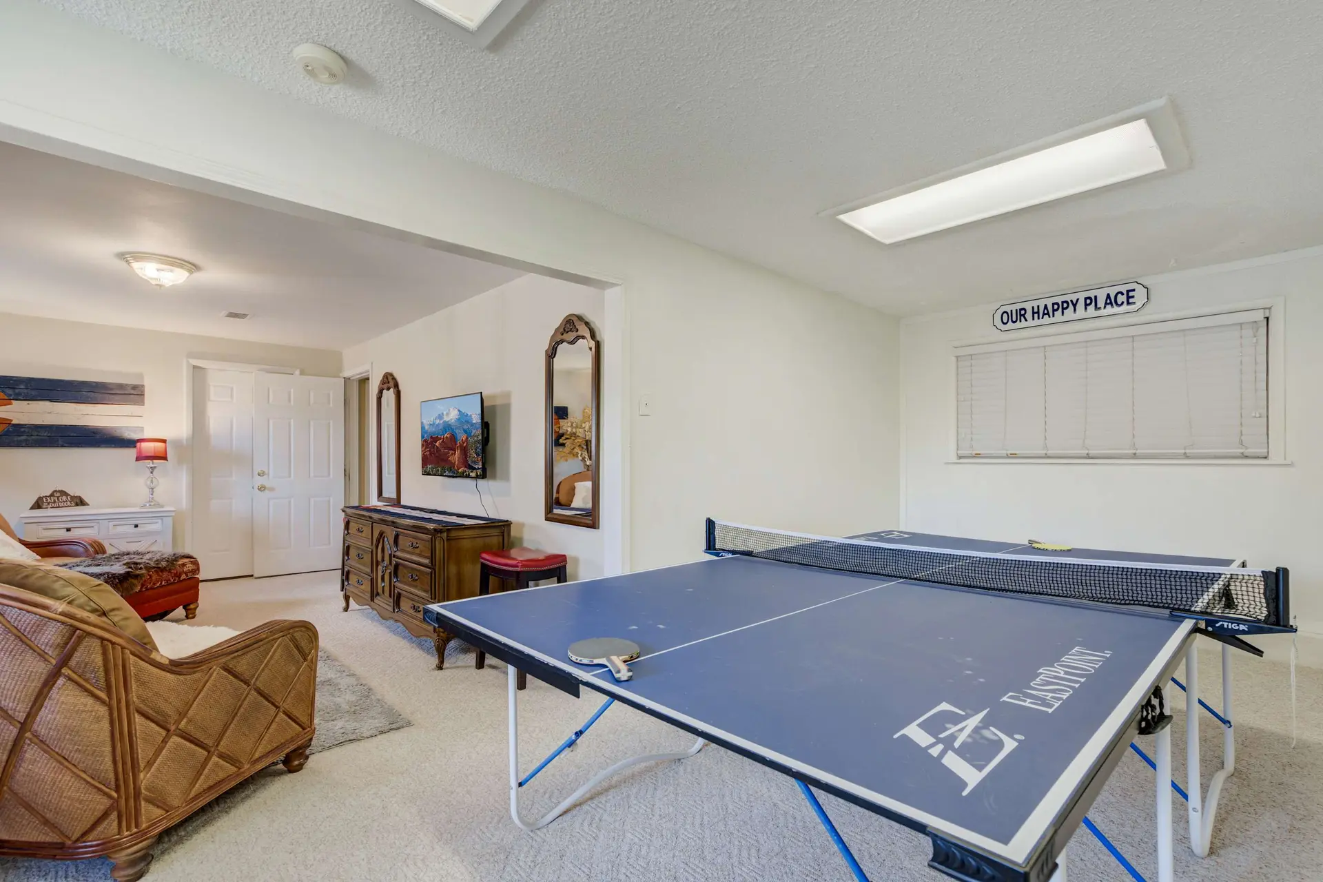 A ping pong table is in the foreground of a recreation room.