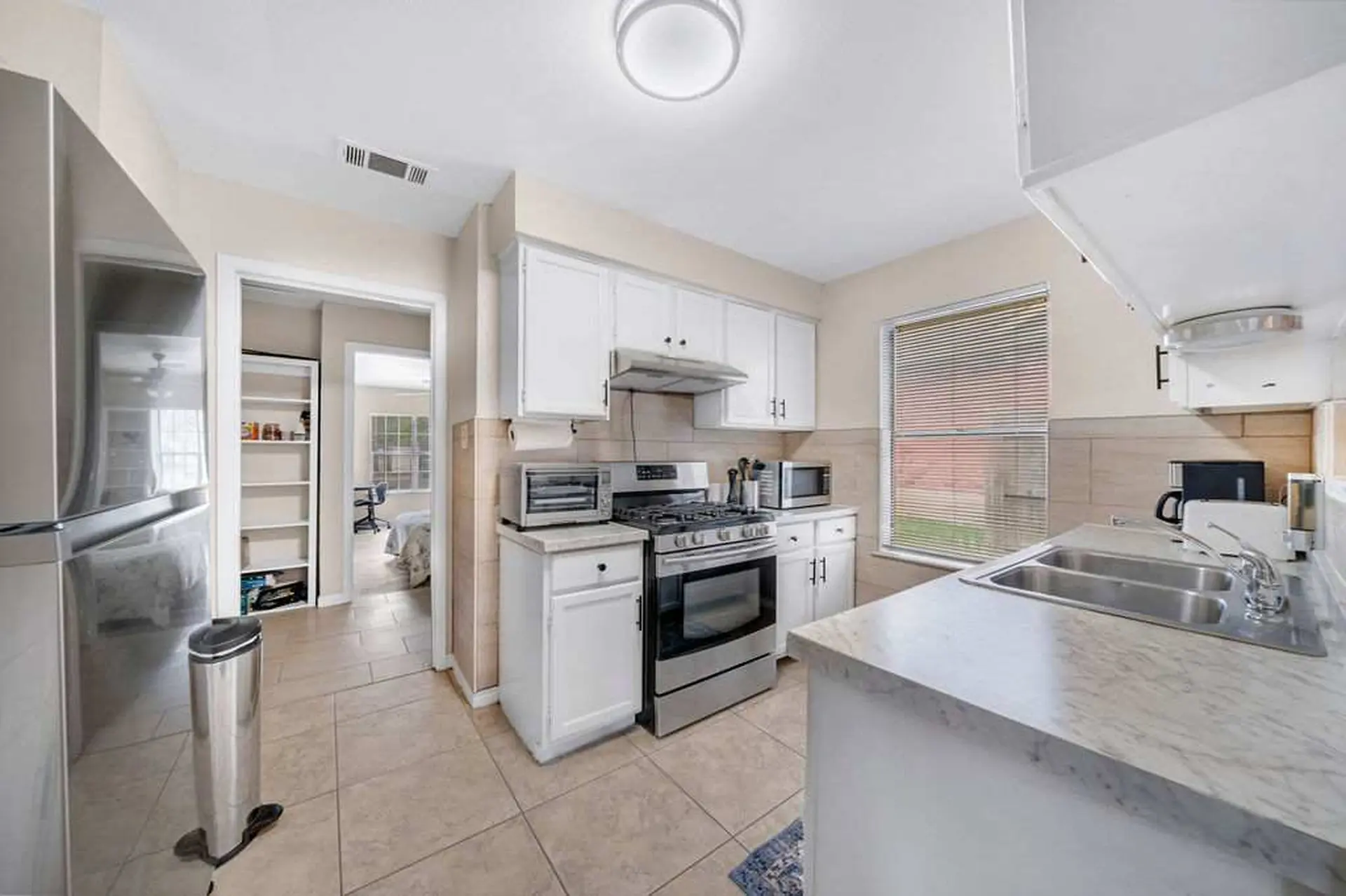 A kitchen with white cabinets, a gas stove, and a double sink.