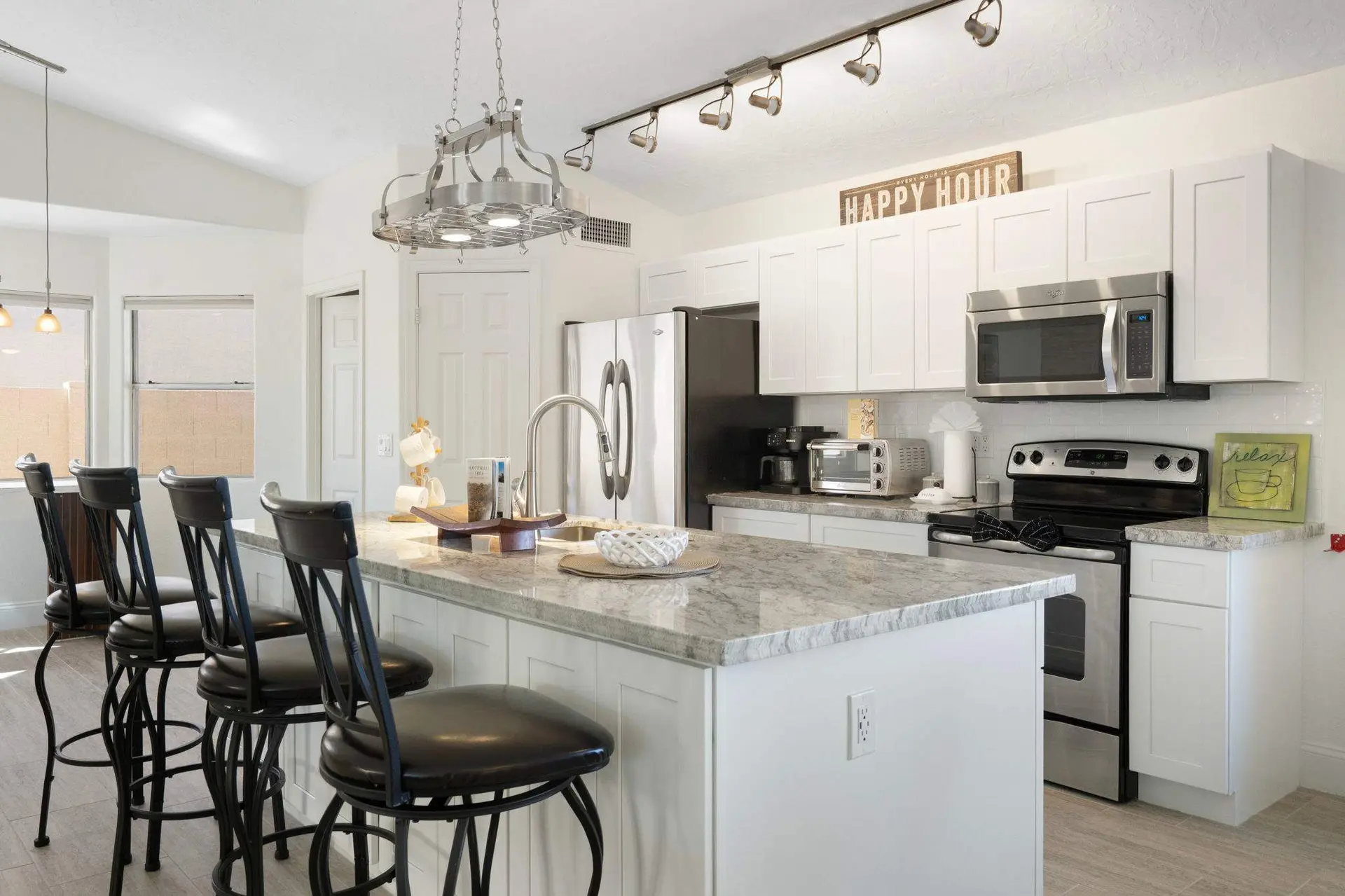 Kitchen island with bar stools, stainless steel appliances, and white cabinets.