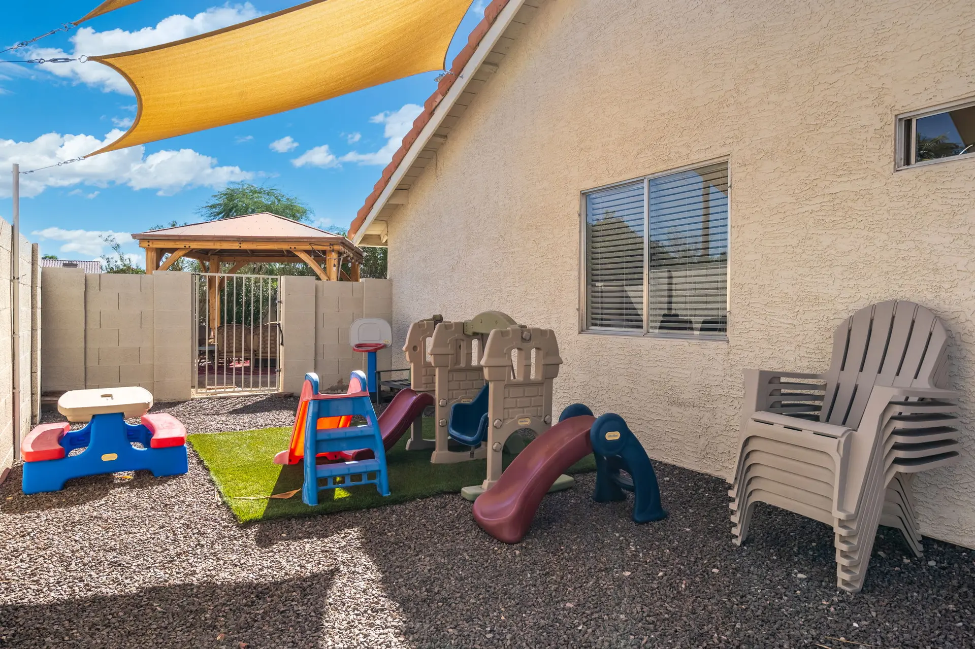 Children's backyard play area with slides, picnic table, and chairs.