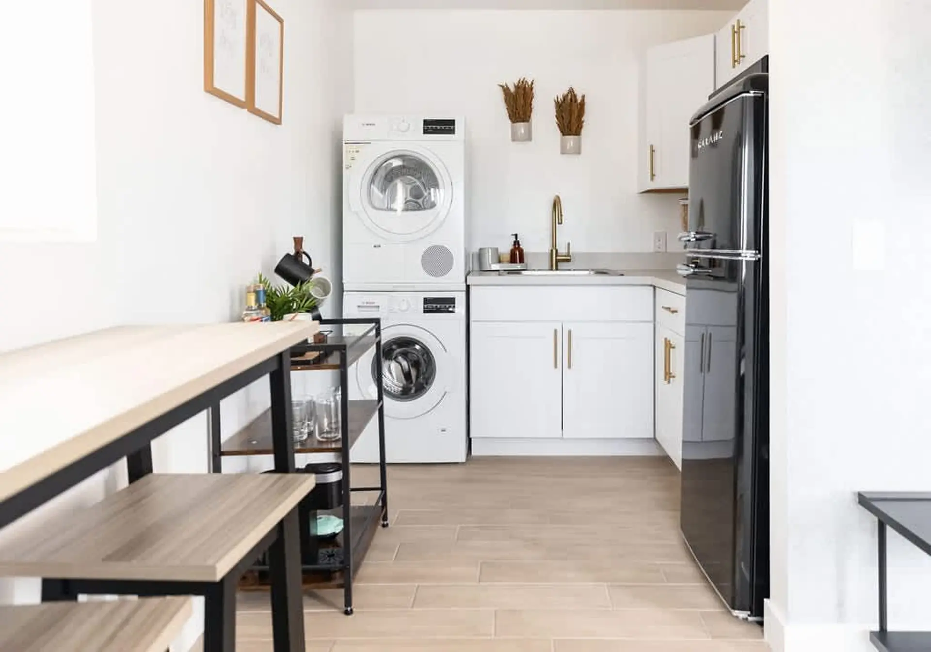A black retro refrigerator stands next to a white kitchen counter with a sink and washing machine.