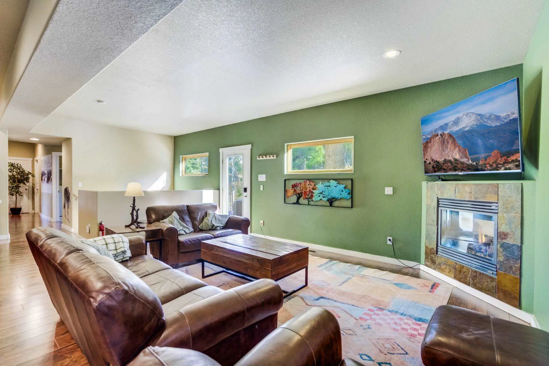 Living room with leather sofas, a coffee table, a fireplace, and a TV.
