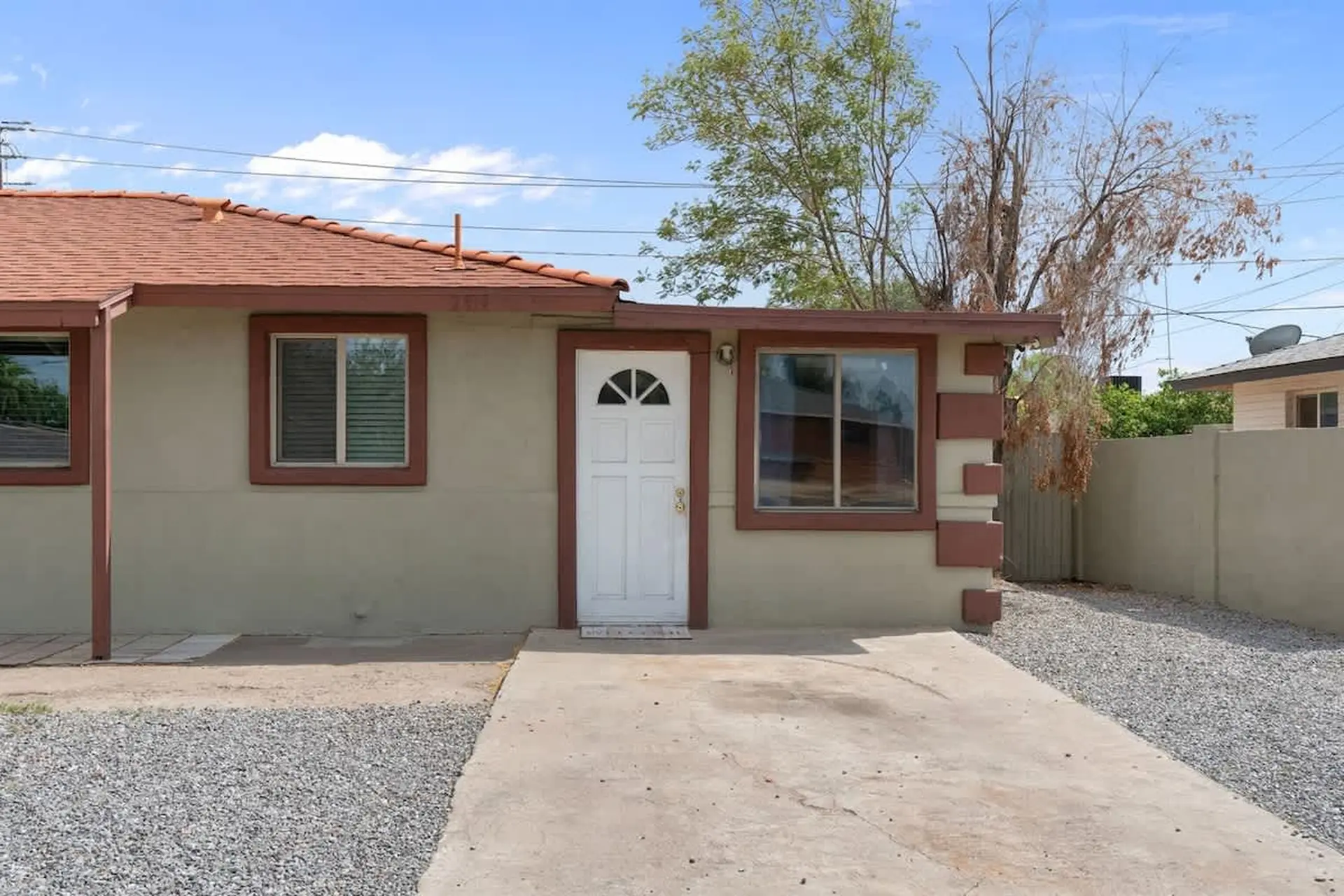 A light beige stucco house with a red tile roof and brown trim.