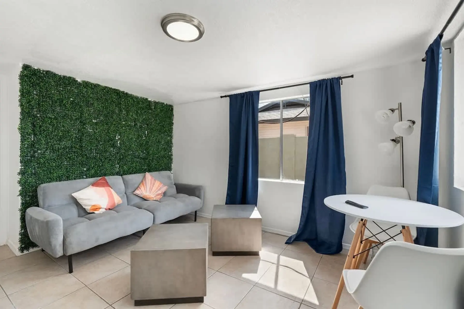 A living room with a grey sofa, green wall, and a round white table.