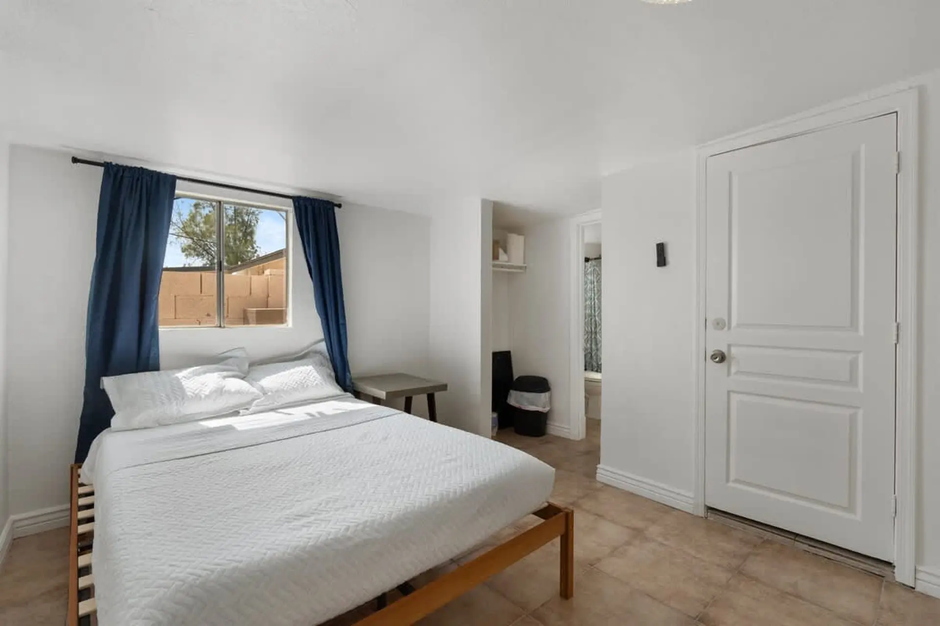 Bedroom with a bed, window, door, and a glimpse into a bathroom.