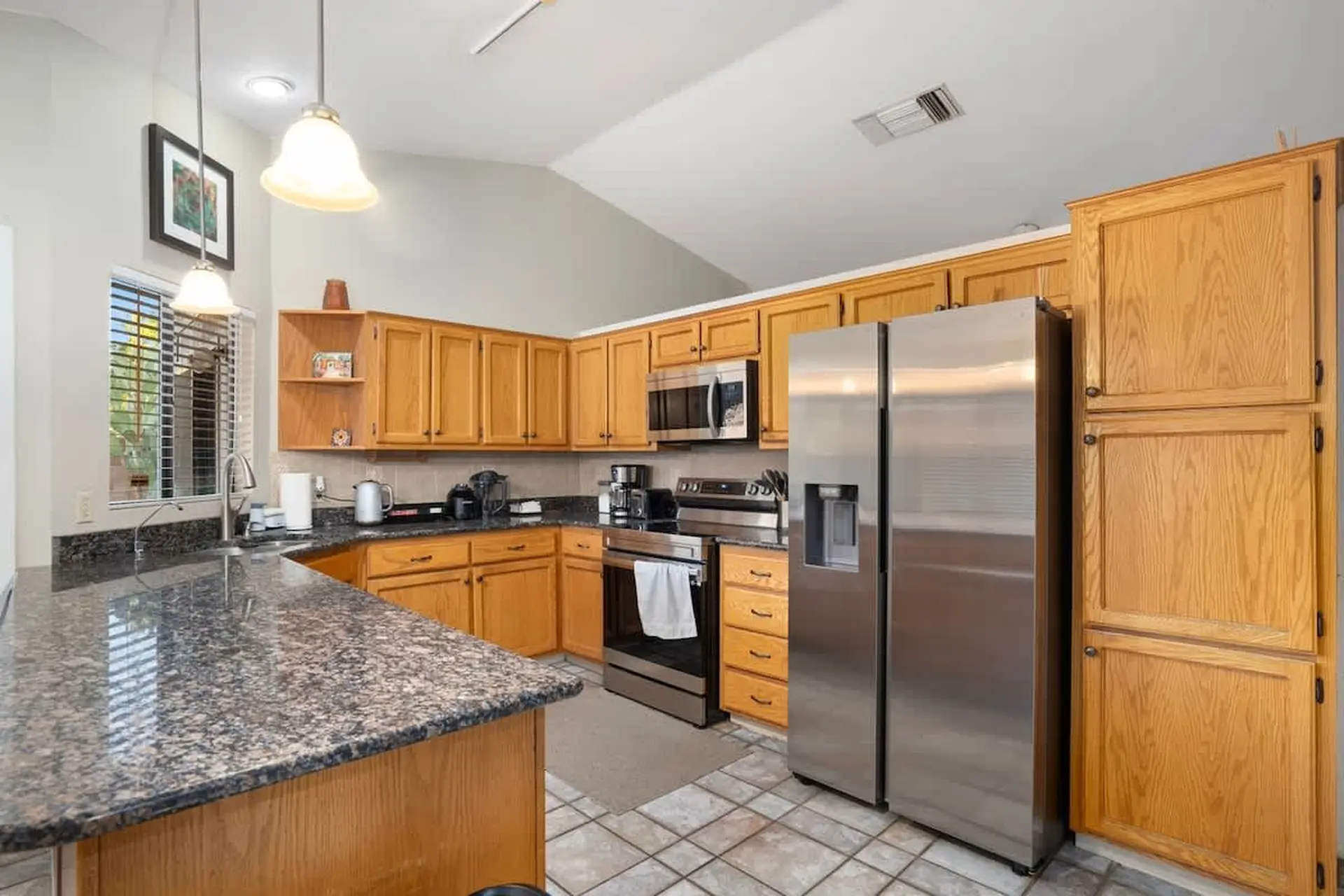 A bright, airy kitchen with warm wood cabinets, granite countertops, and stainless steel appliances.