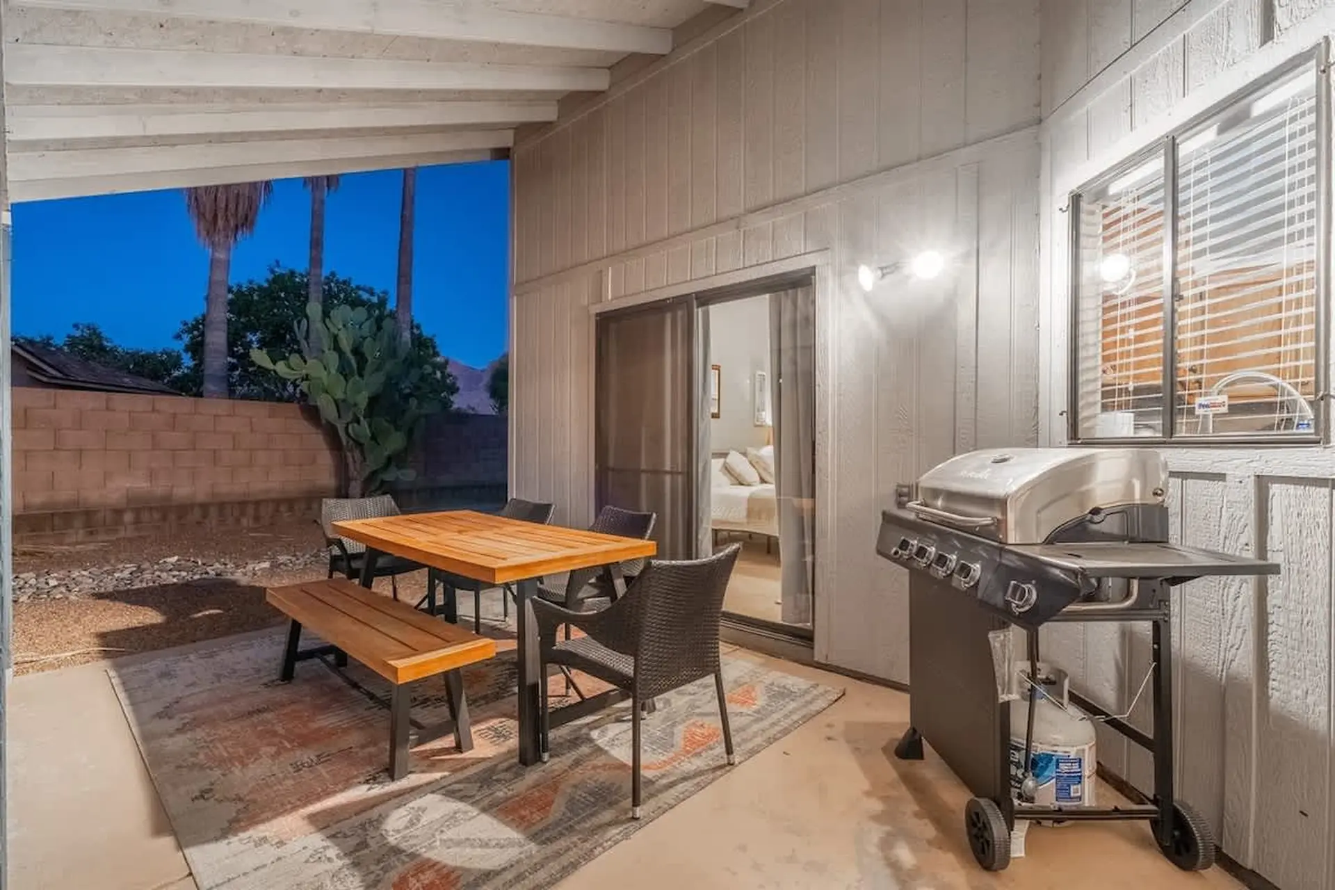 Covered patio with dining table, chairs, grill, and outdoor view.