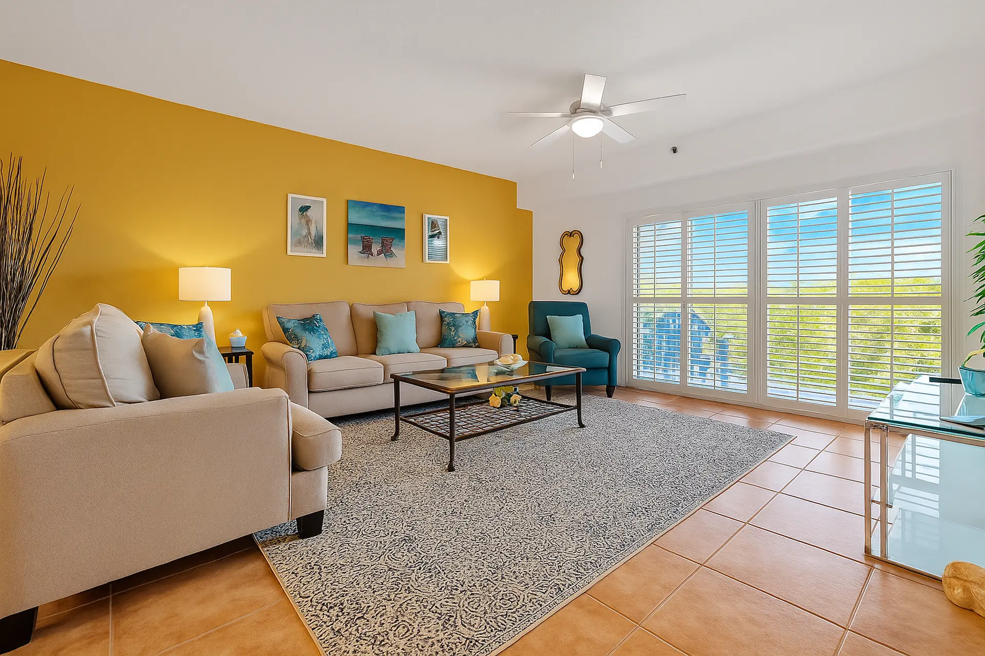 A bright living room with a yellow accent wall, beige sofas, and a coffee table.