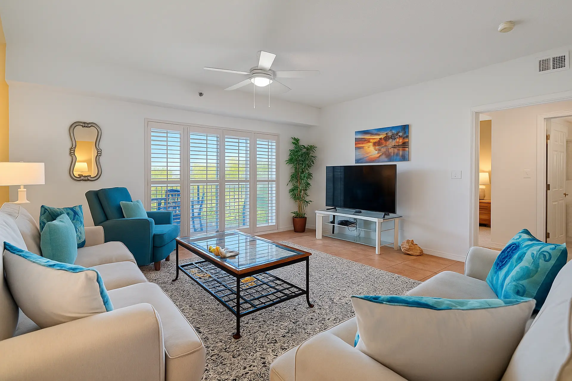 Living room with white sofas, blue accent chairs, a coffee table, and a TV.