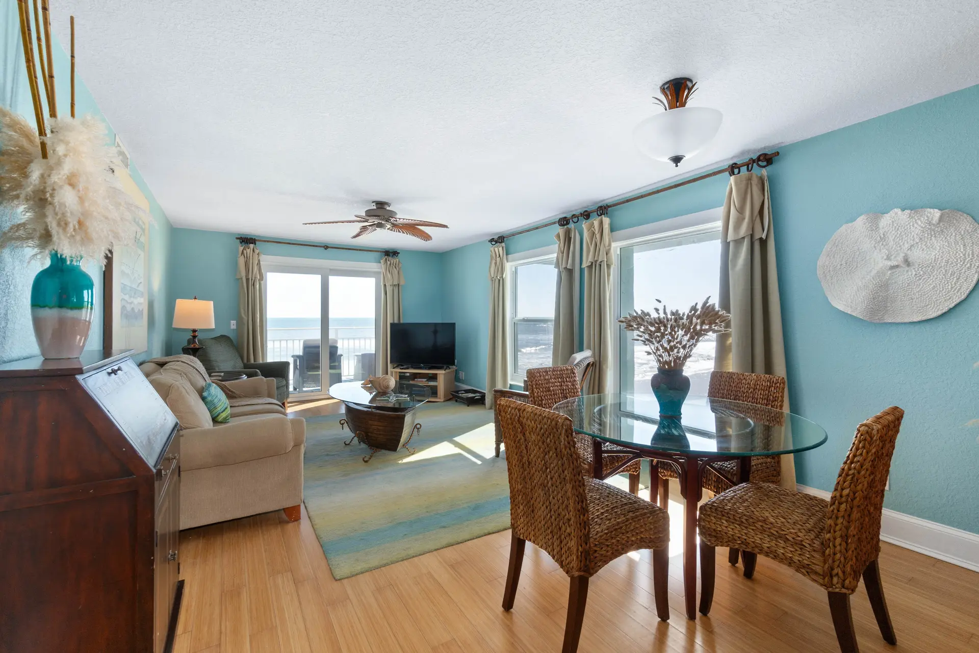 Living room with a dining table and chairs, a sofa, a TV, and a view of the ocean.