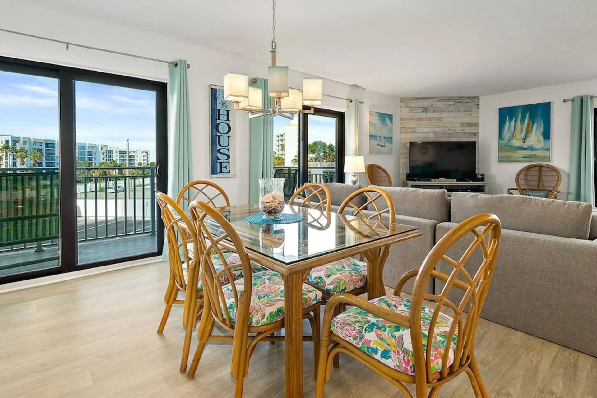 A dining room with a glass-top table and wicker chairs with floral cushions.