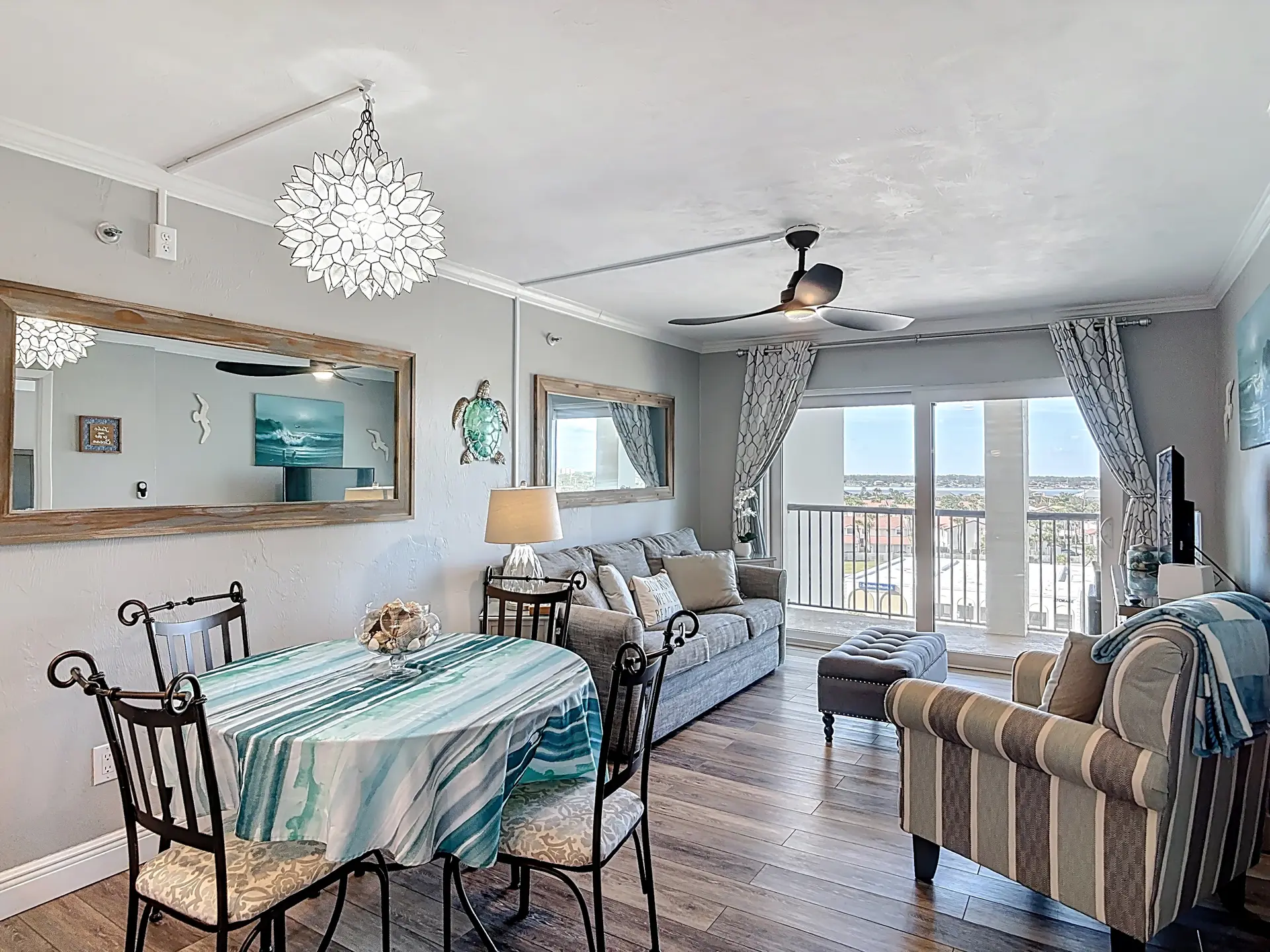 Coastal living room with a dining table, couch, armchair, and a large mirror.
