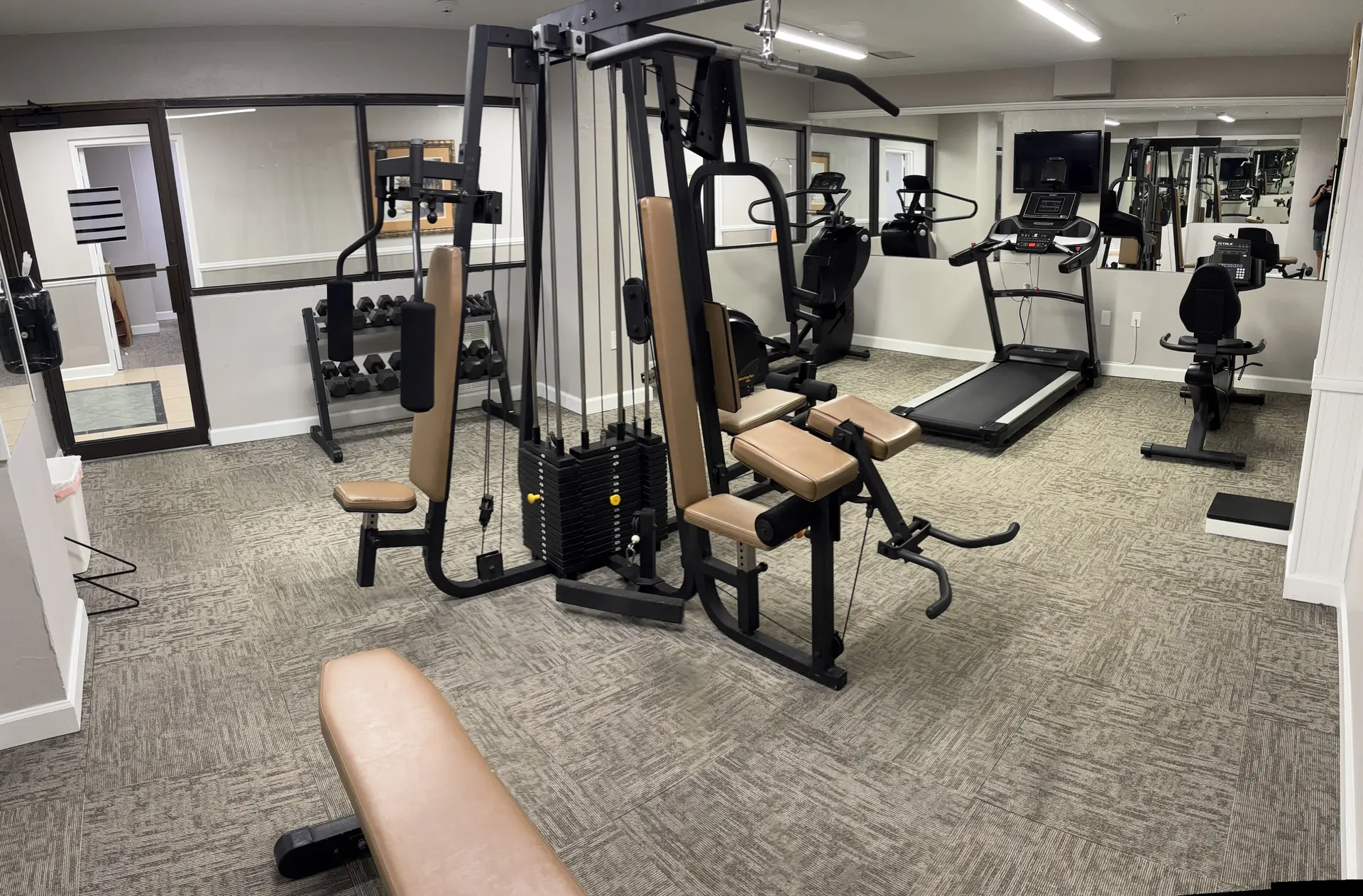 A gym with exercise equipment and mirrors.