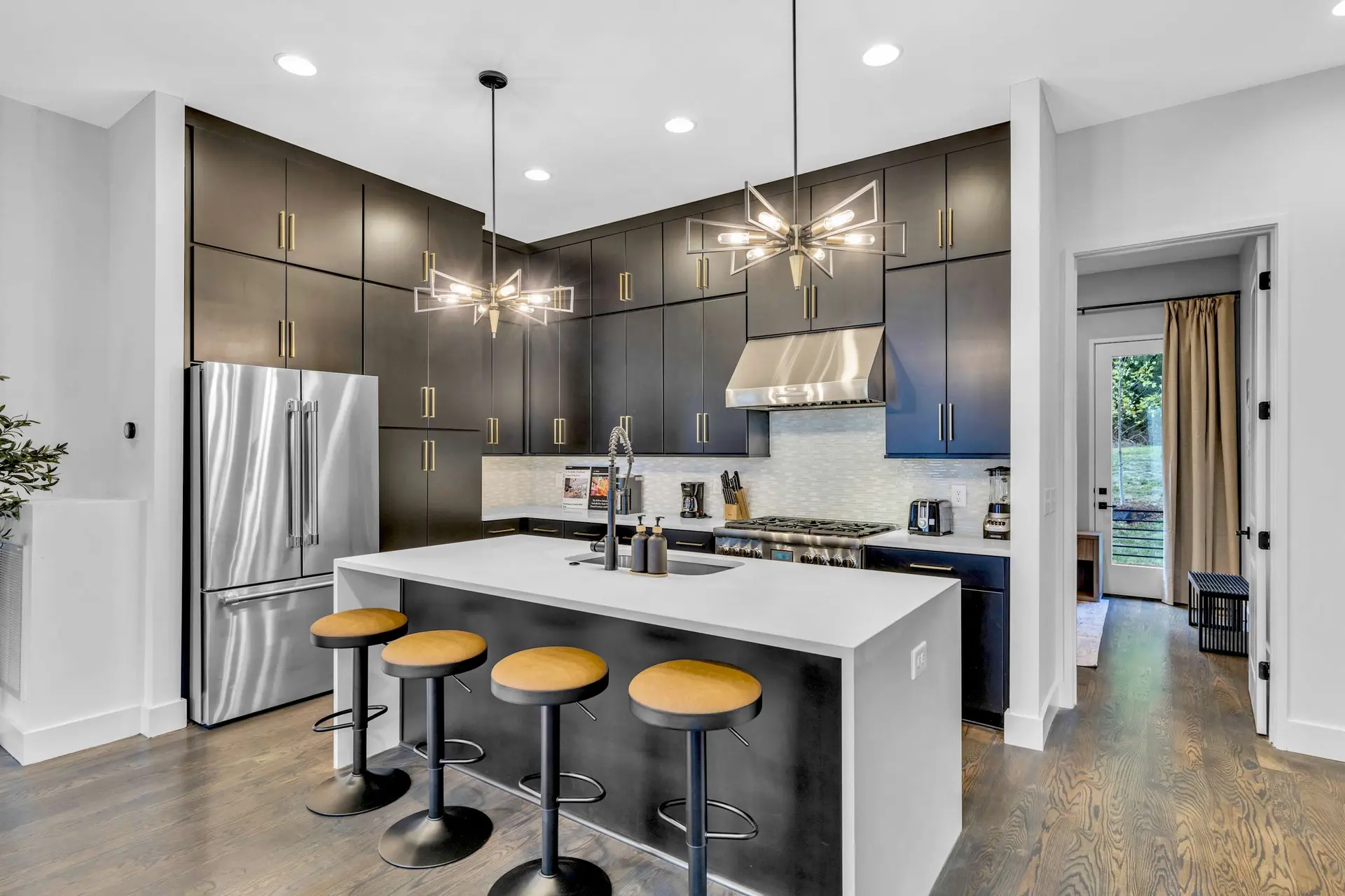 Modern kitchen with dark cabinets, stainless steel appliances, and a large island with bar stools.