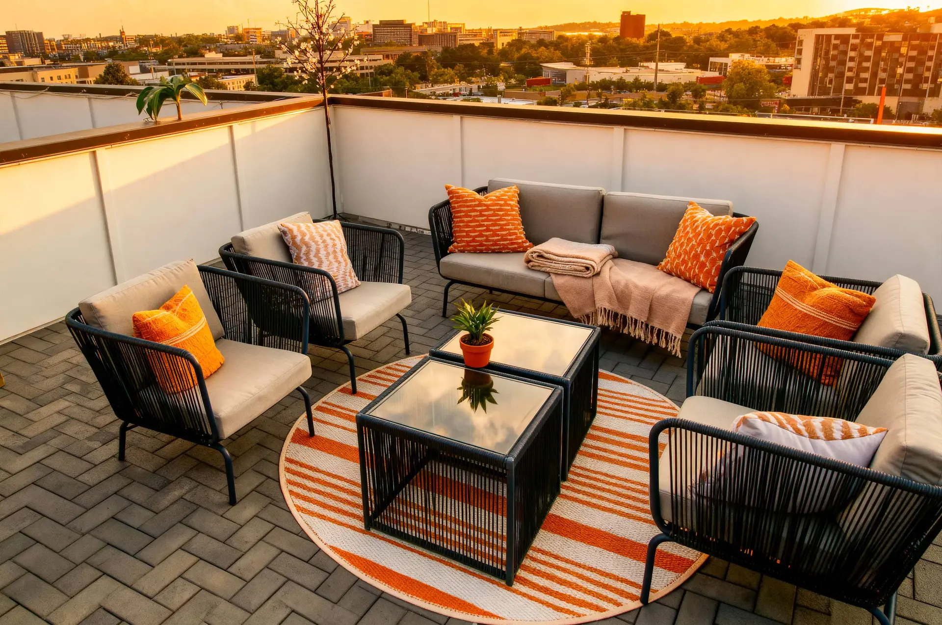 Outdoor rooftop patio with seating and a cityscape view at sunset.