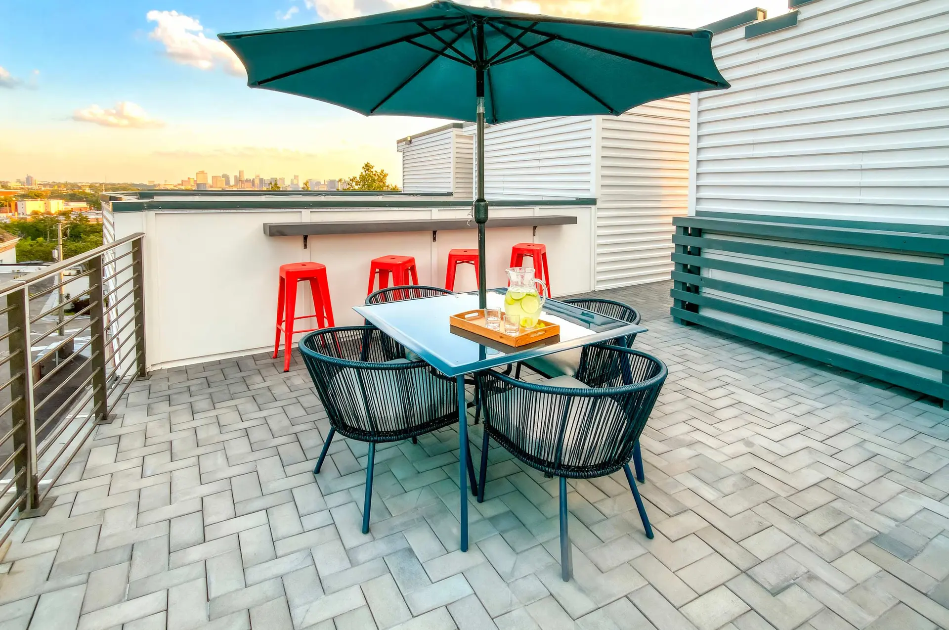 Rooftop patio with a table, chairs, and a city view at sunset.