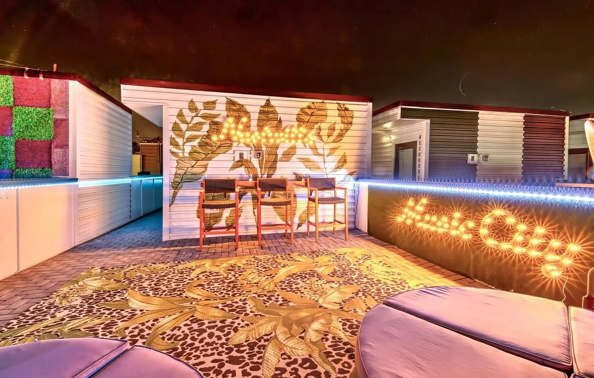 A rooftop patio at night with string lights and plush seating.