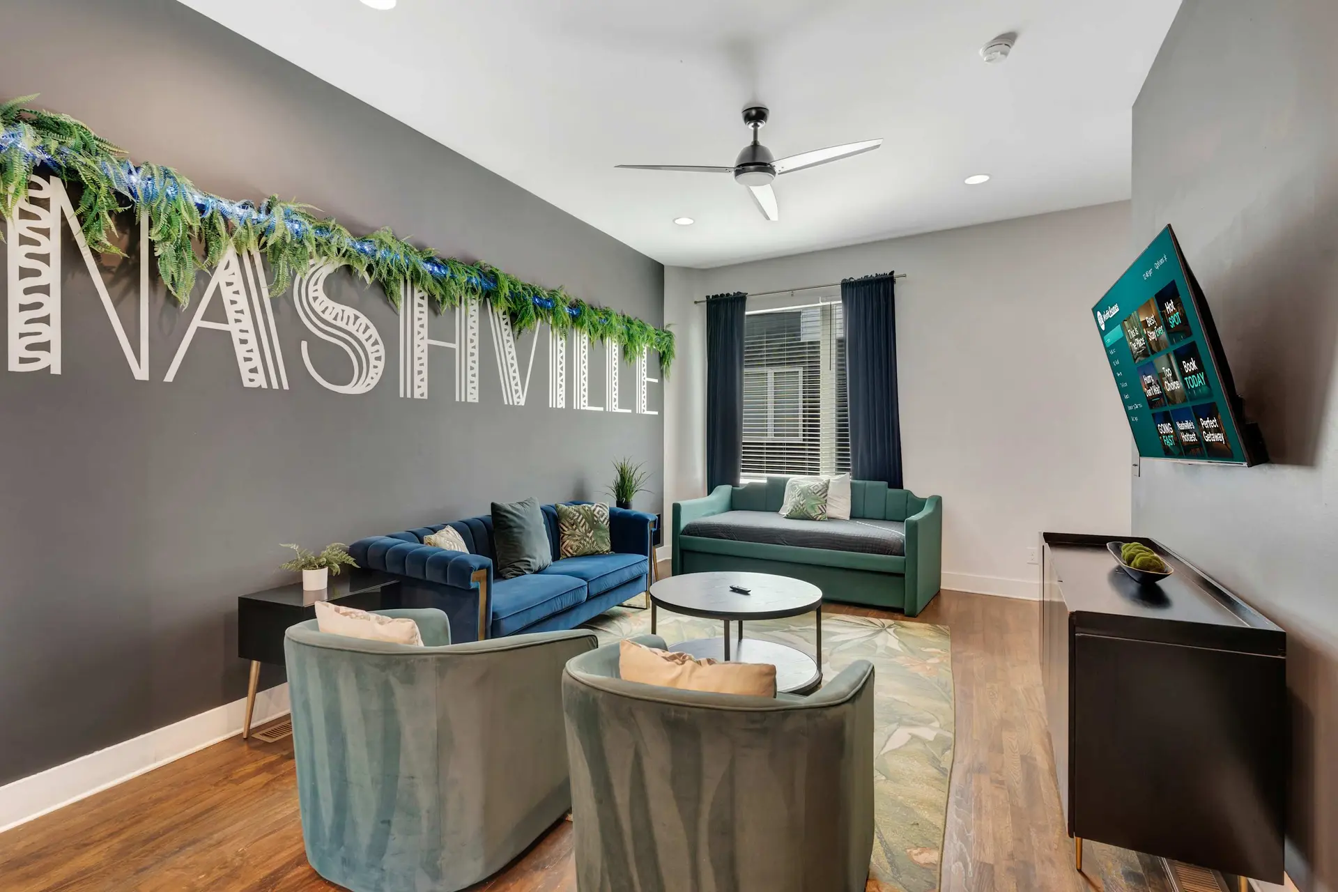 Living room with blue and green furniture, a TV, and "Nashville" decor.