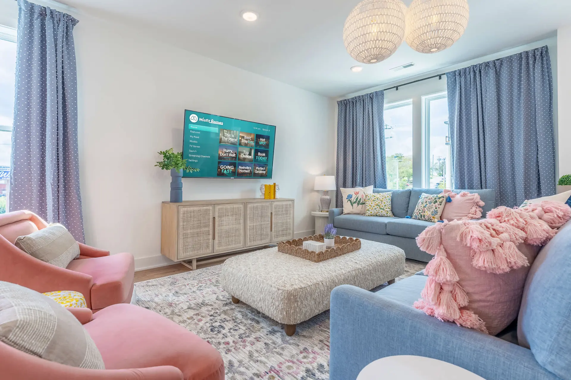 A living room with blue curtains, pink chairs, and a blue sofa.