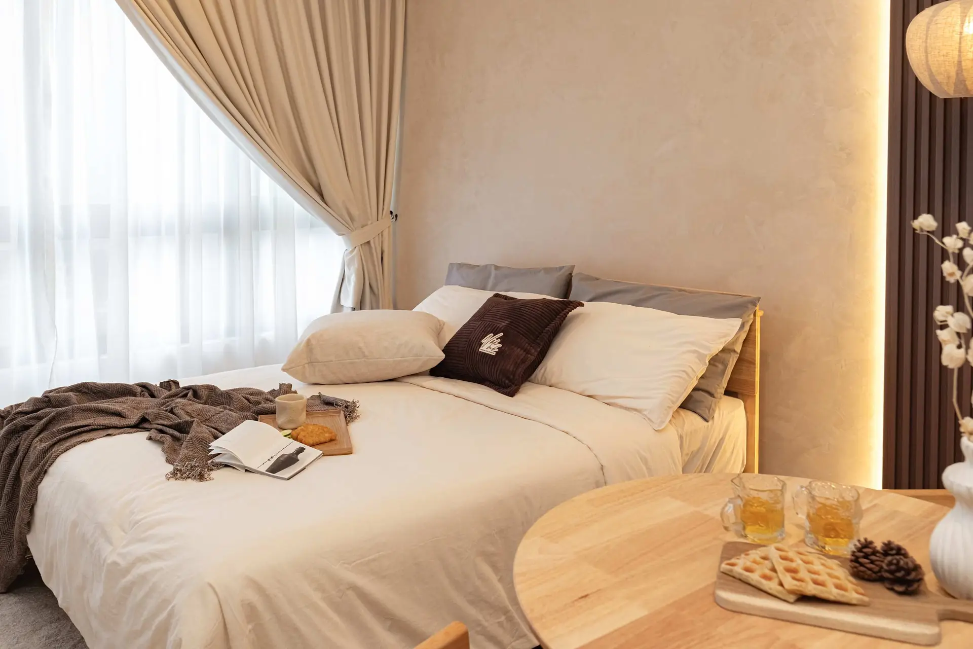 Cozy bedroom with bed, curtains, and a tray of snacks on a table.