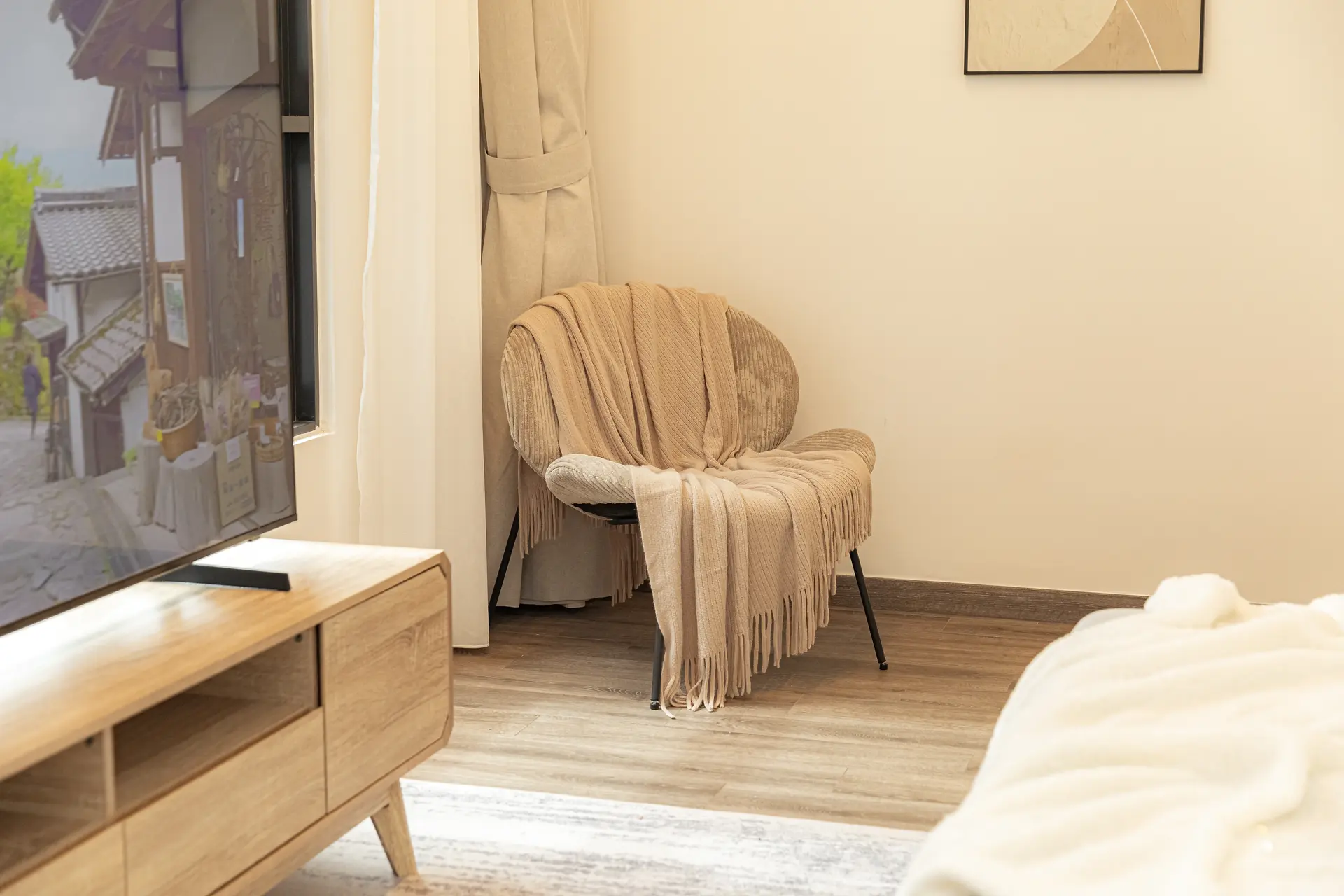 A beige throw blanket with fringes covers a round chair.