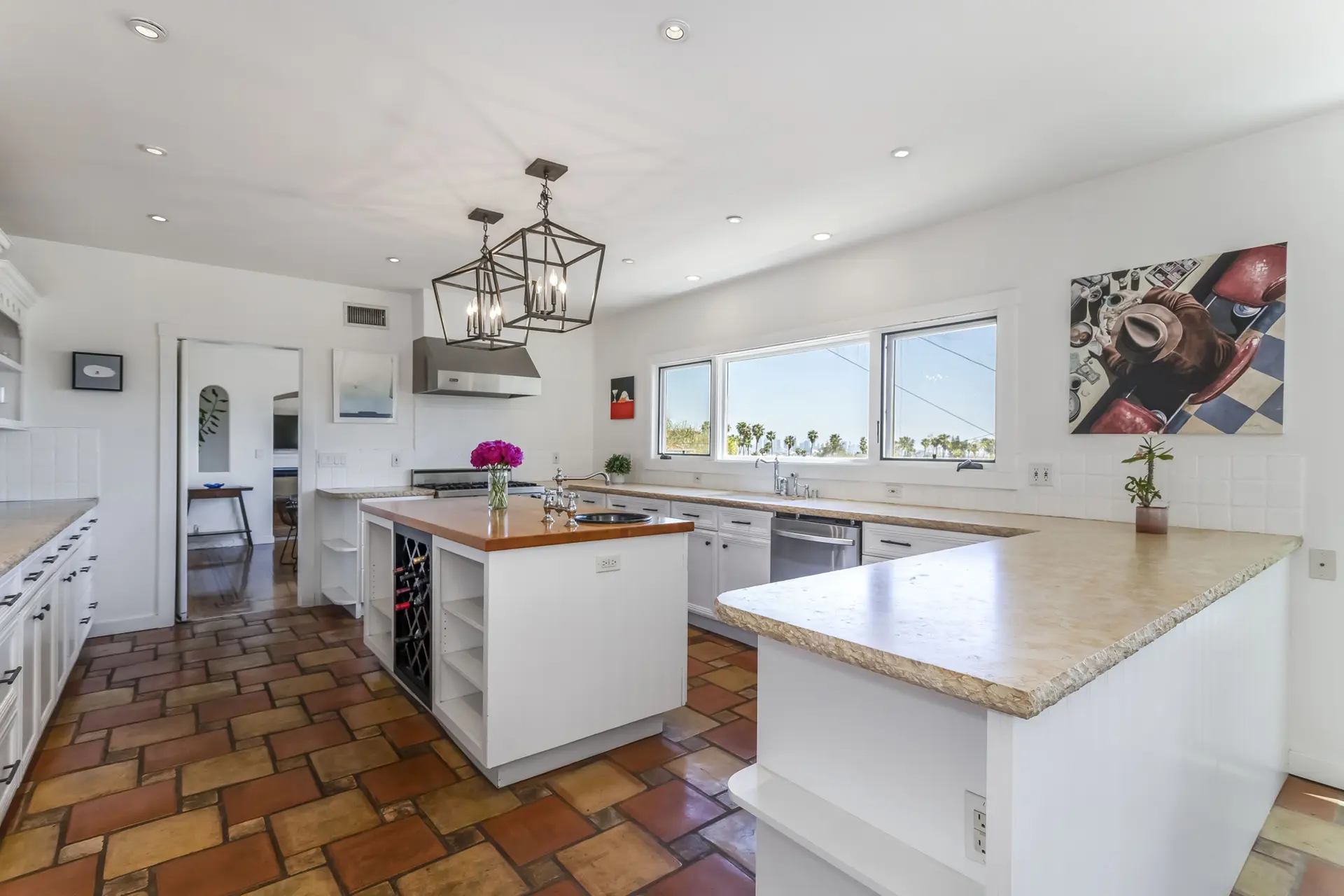 A bright and airy kitchen with white cabinets, a large island, and terracotta tile flooring.