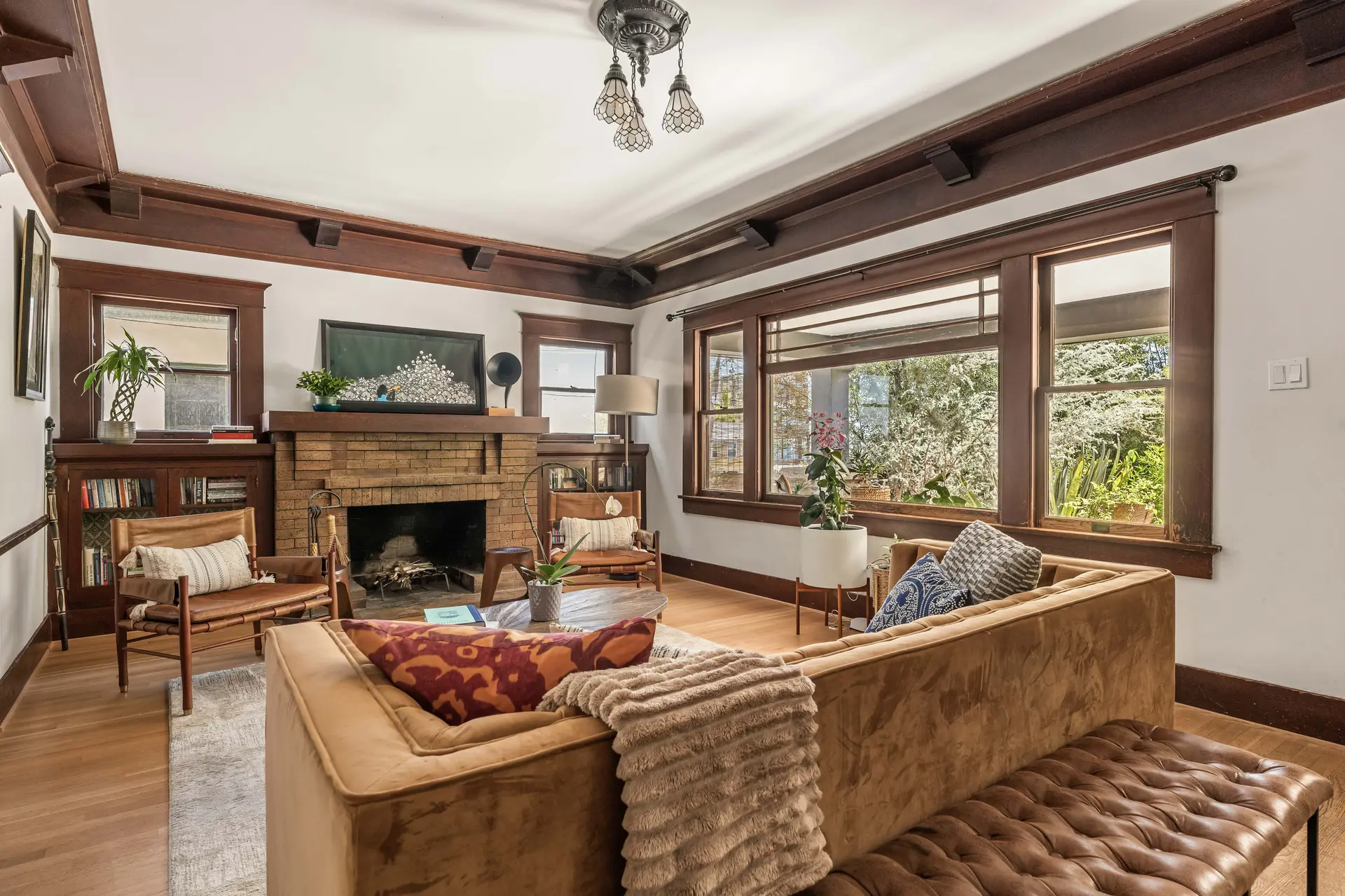 Cozy living room with brown suede couch, fireplace, and large windows.