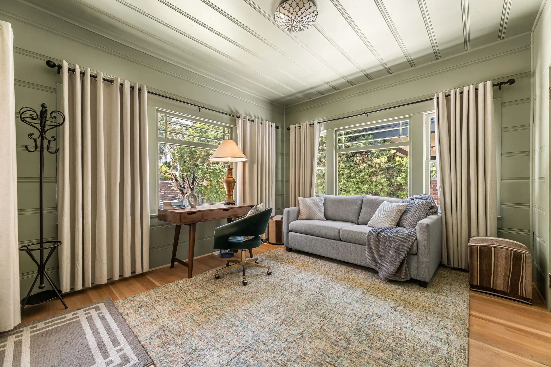 Living room with couch, desk, chair, and decorative ceiling.