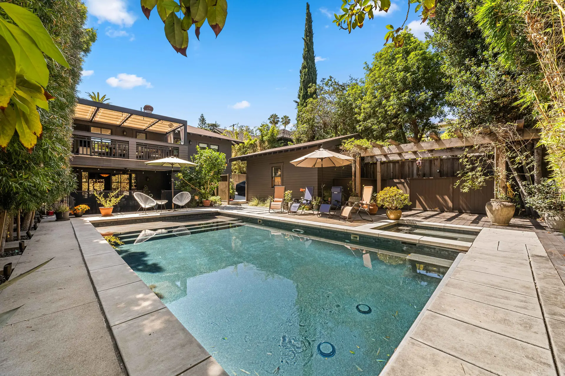 Backyard with a pool, lounge chairs, and a dark brown house.