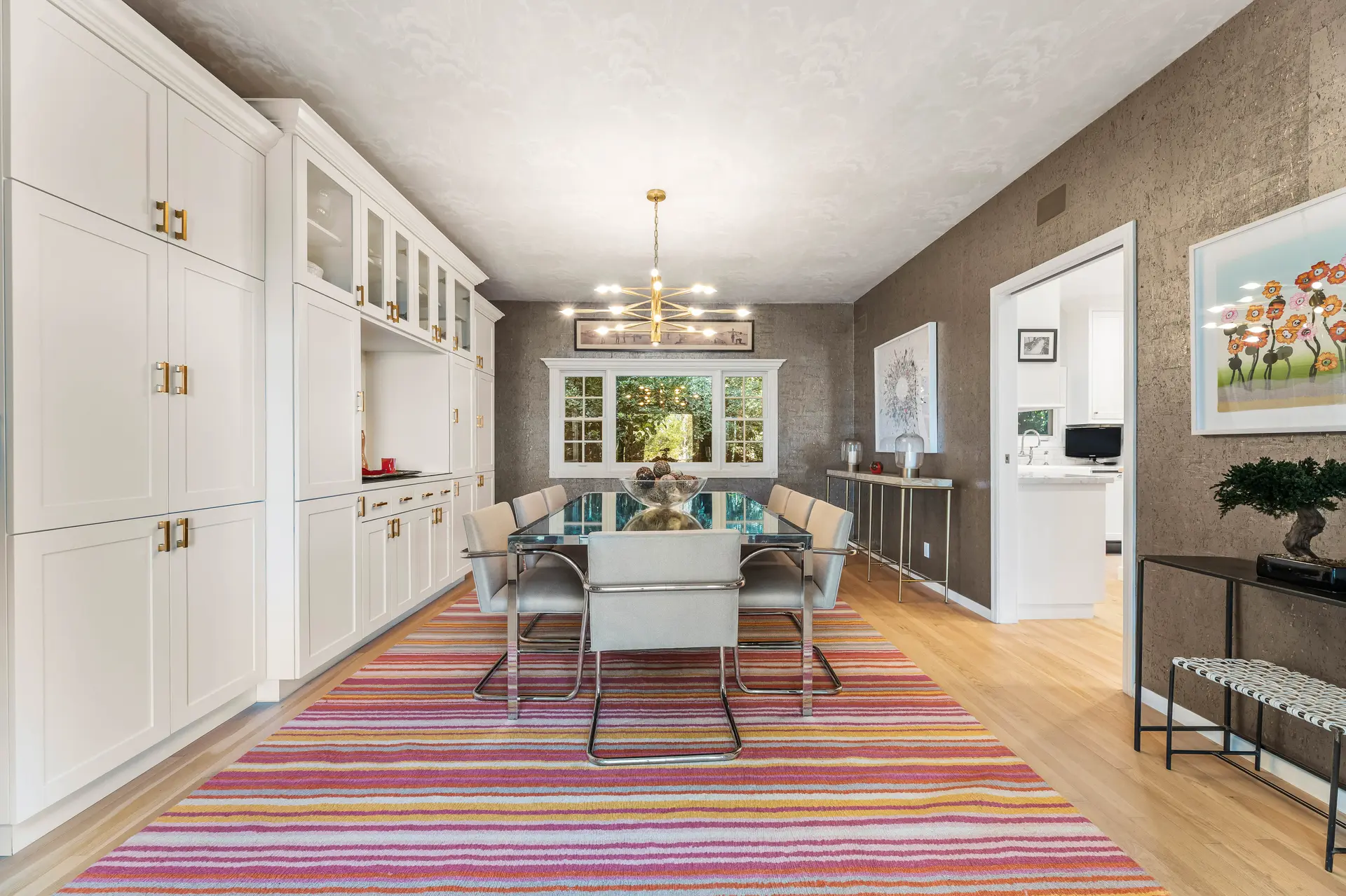 A bright and modern dining room with a large glass table and chairs.