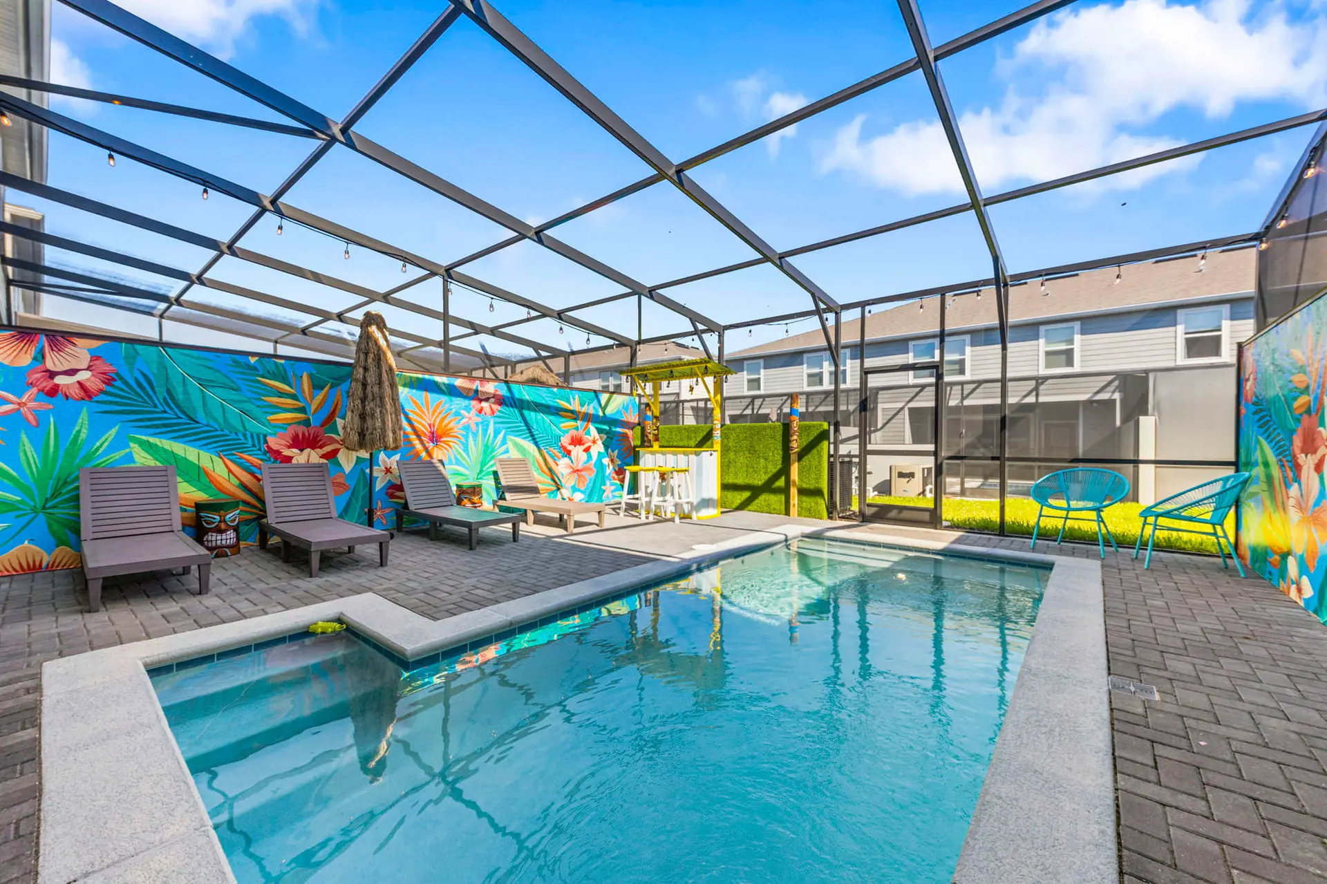 A backyard pool area with lounge chairs, a tiki bar, and colorful tropical murals.