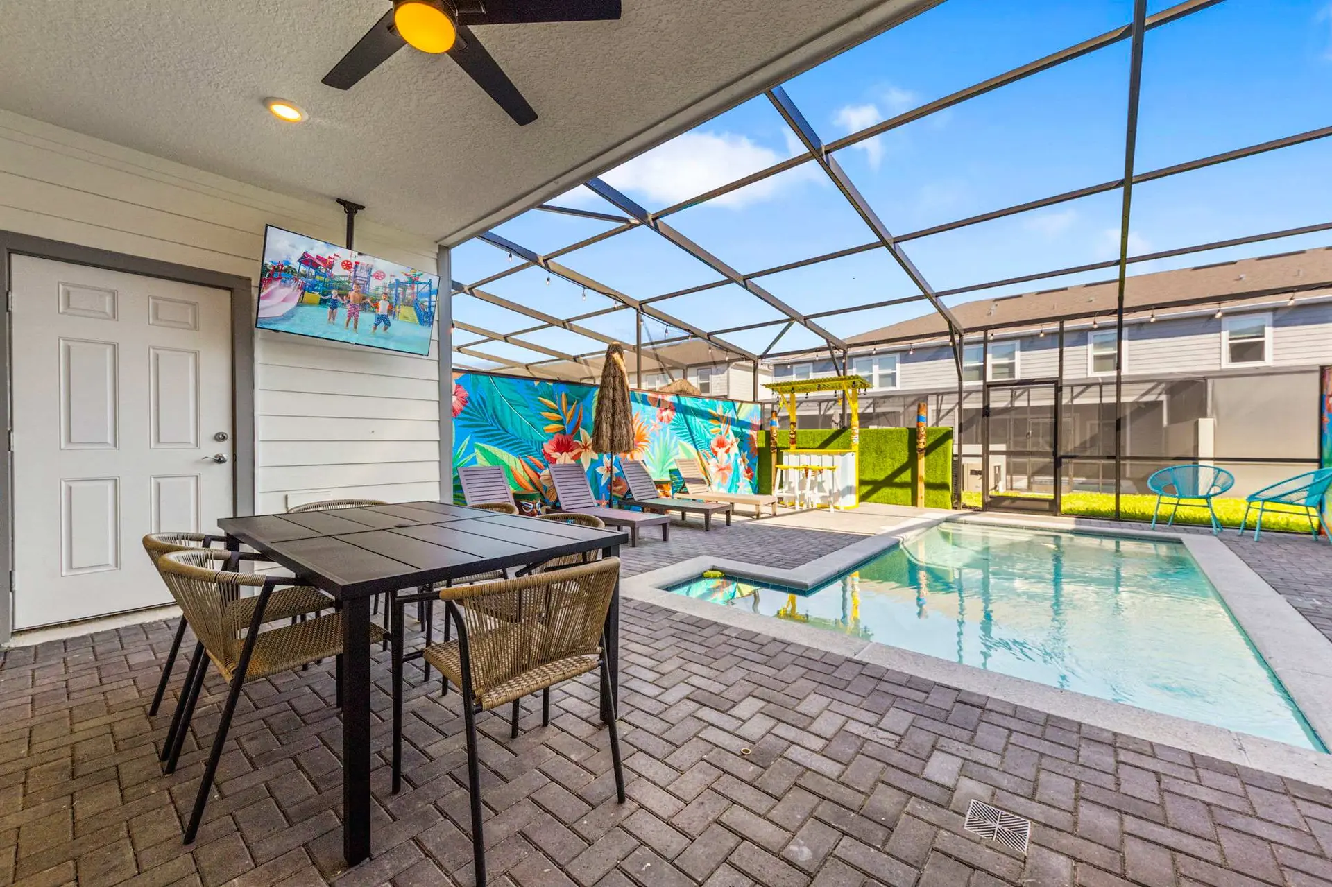 Outdoor dining area and pool with a tropical mural and bar.
