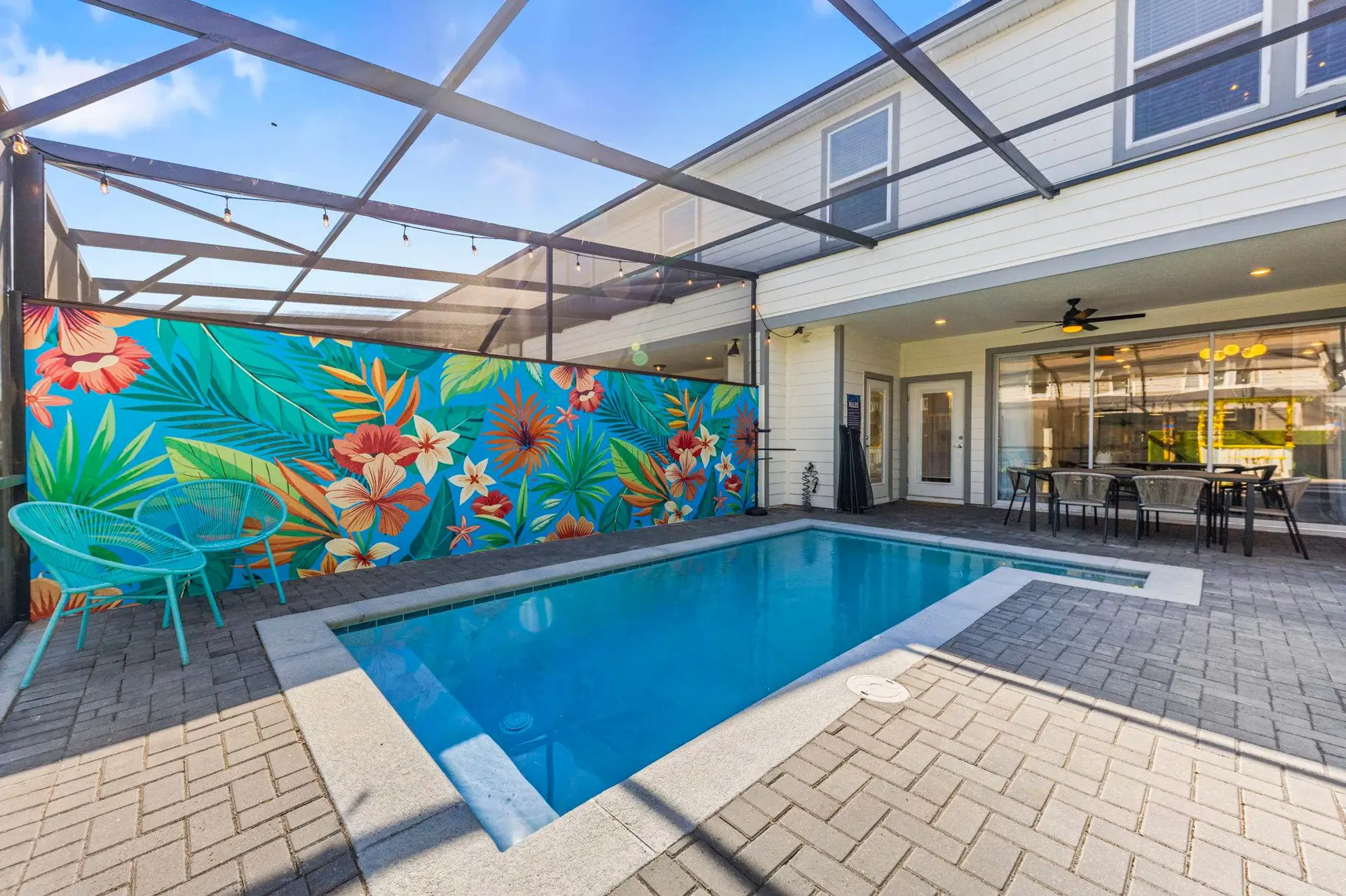 A backyard with a pool and tropical mural.