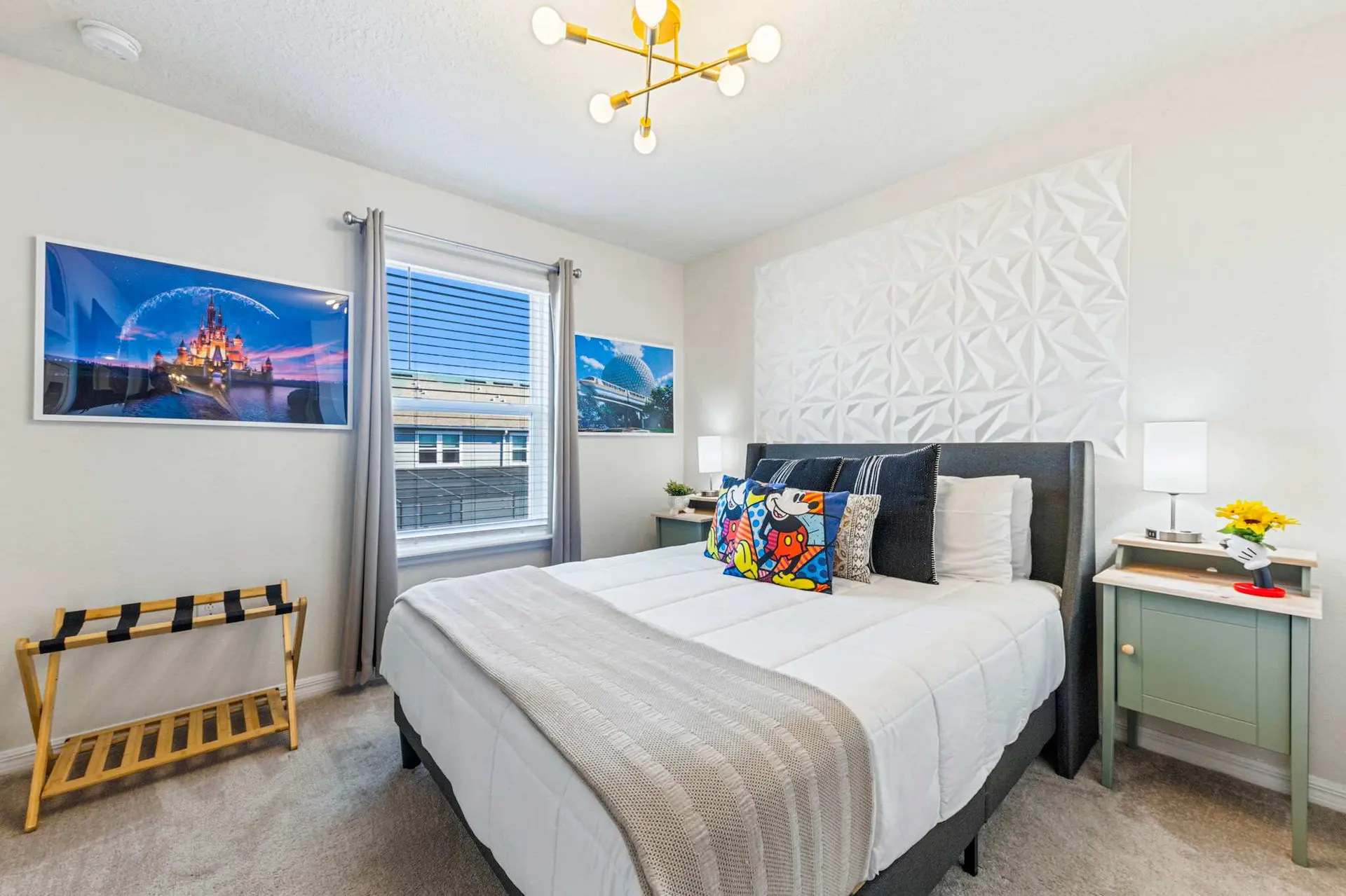 A Disney-themed bedroom with a king-size bed, colorful Mickey Mouse pillows, and castle artwork.