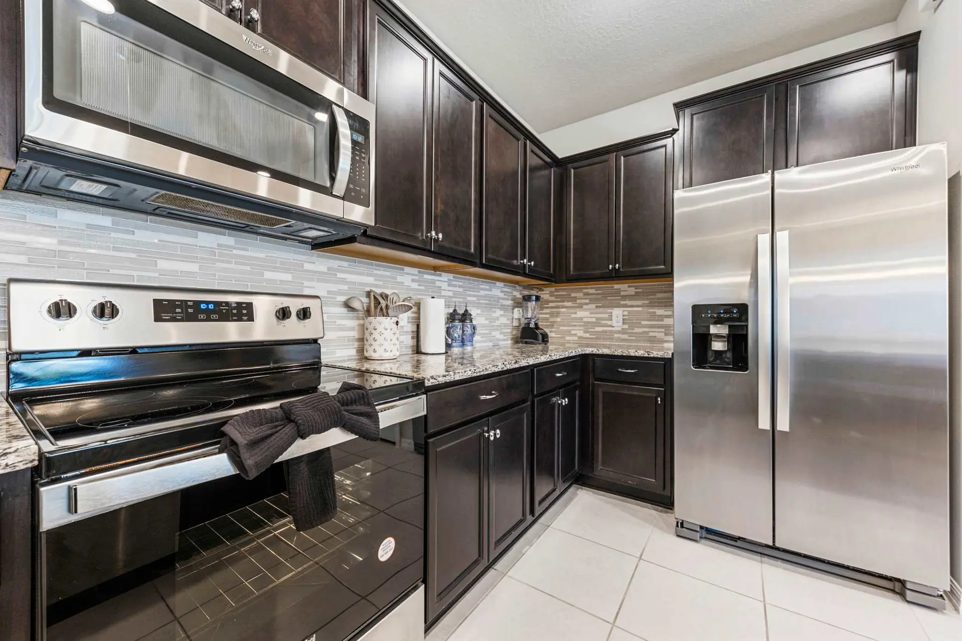 A stainless steel refrigerator sits next to dark brown kitchen cabinets.