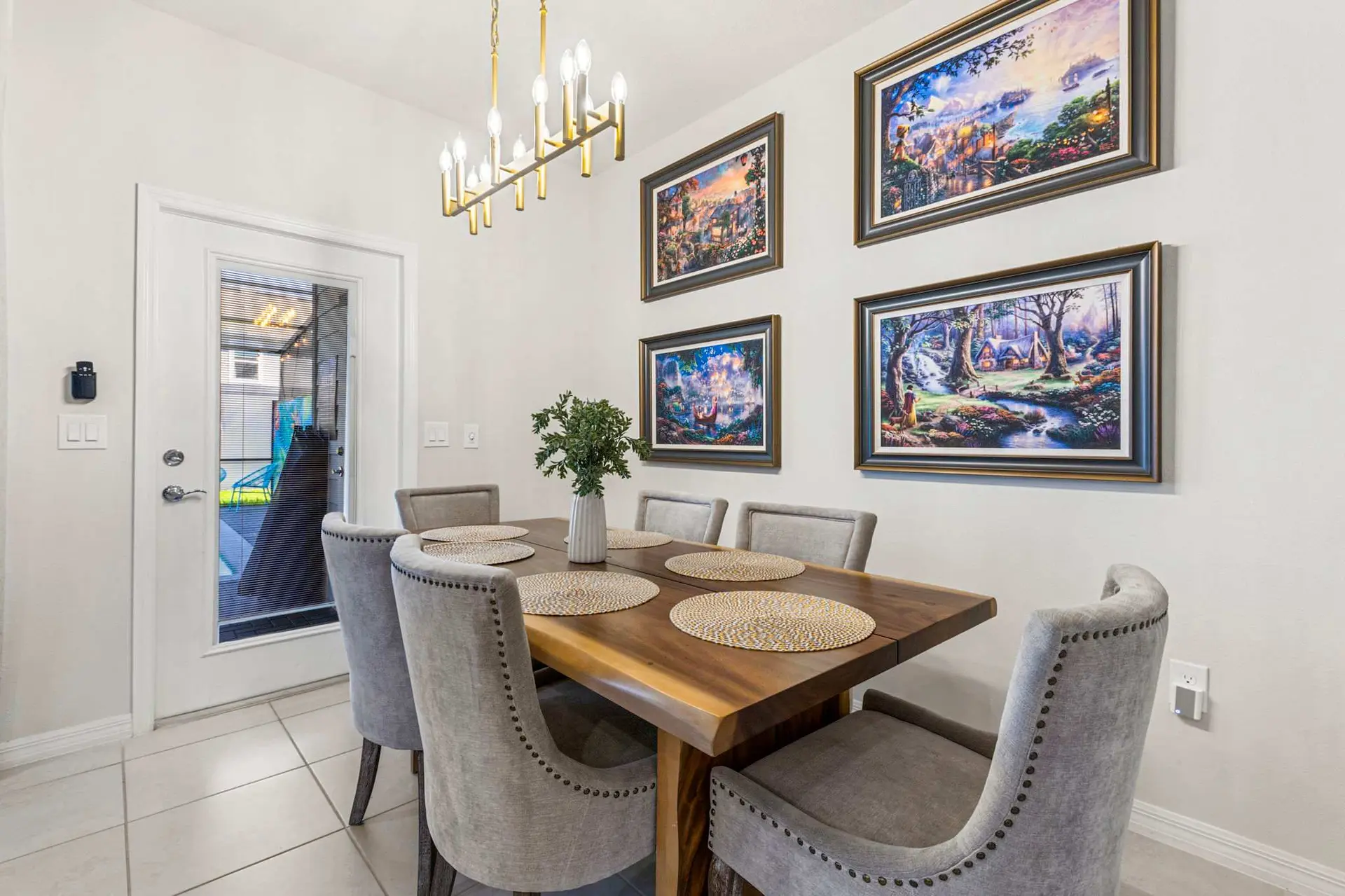 A dining room with a wooden table, upholstered chairs, and framed artwork on the wall.