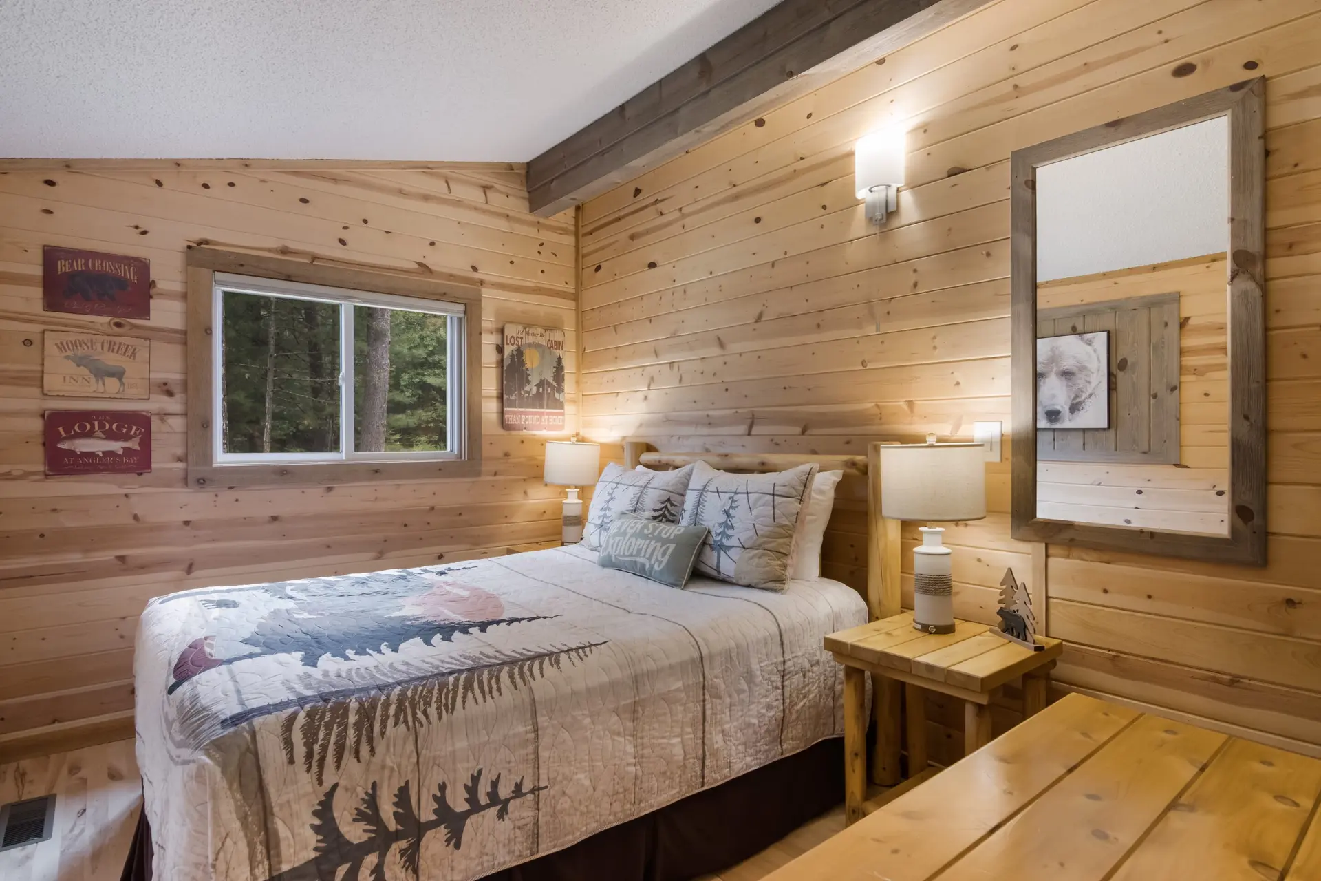 Cozy bedroom with log walls, a quilt bedspread, and a forest view.