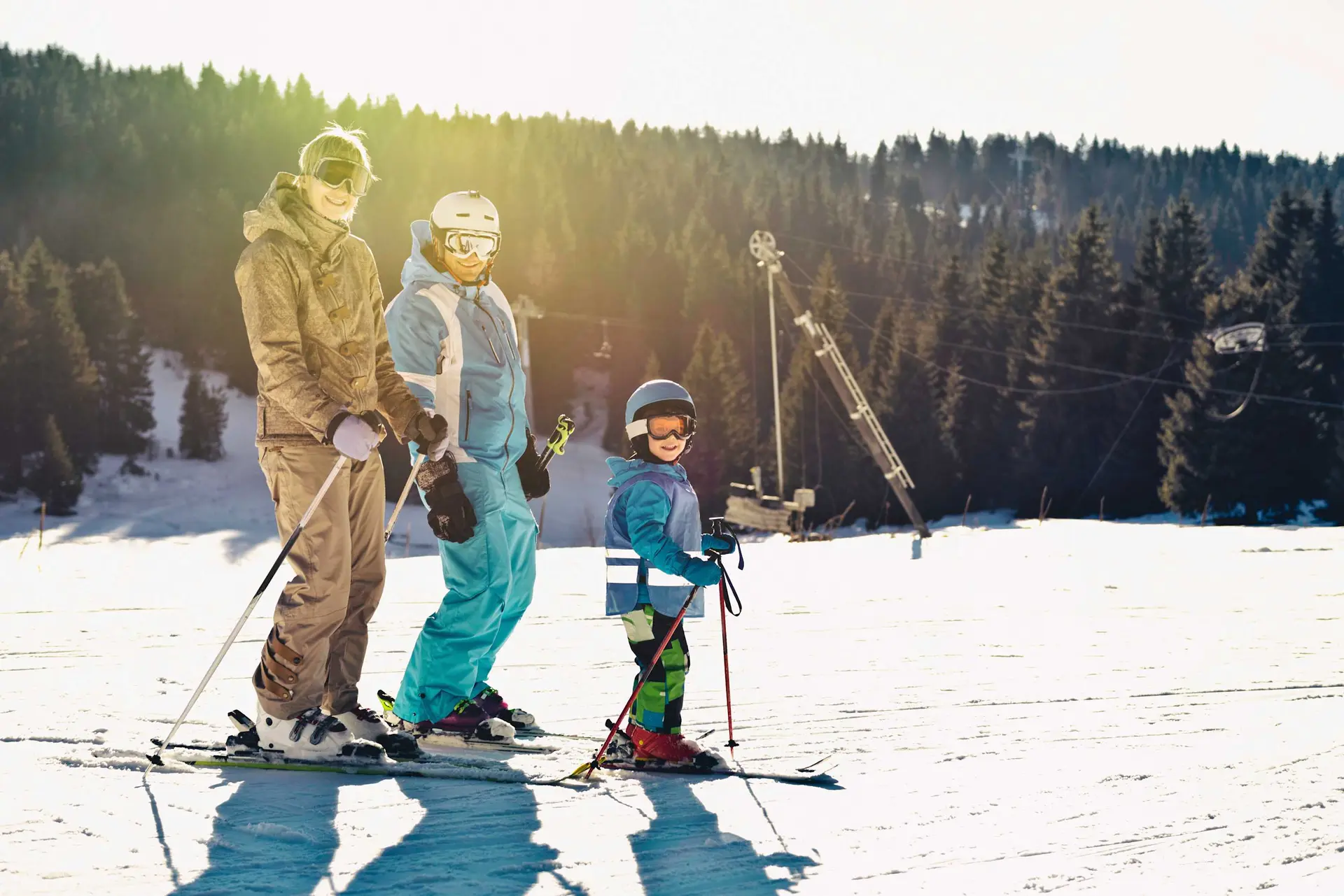 A family skis down a slope on a sunny day.