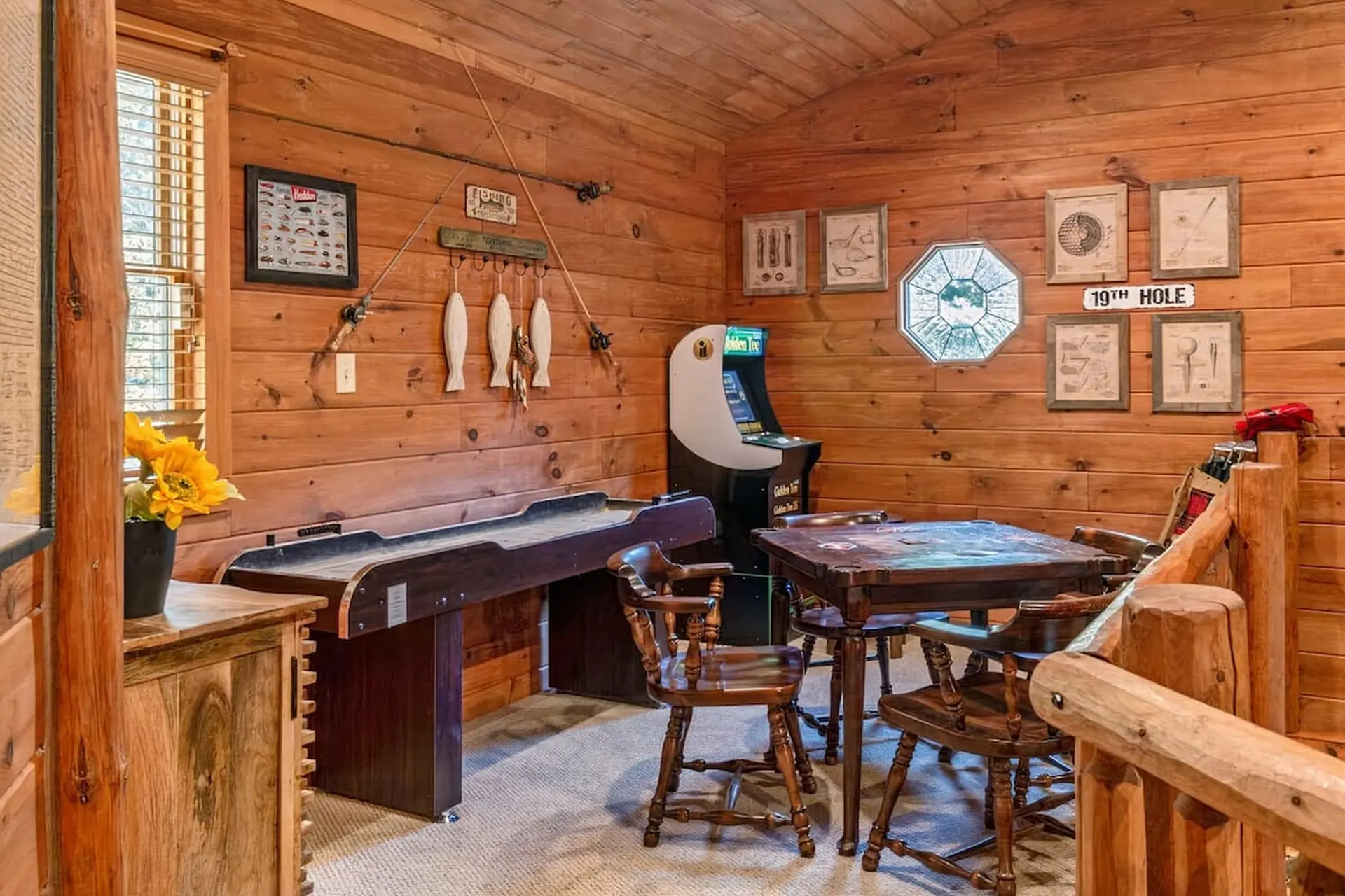 A wooden game room with a shuffleboard, arcade game, and card table.