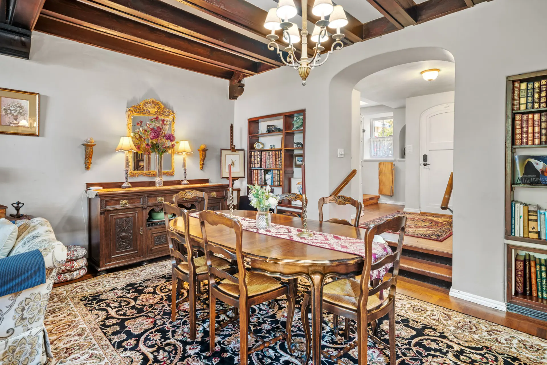 A dining room with a dark wood table and chairs, ornate buffet, and Persian rug.
