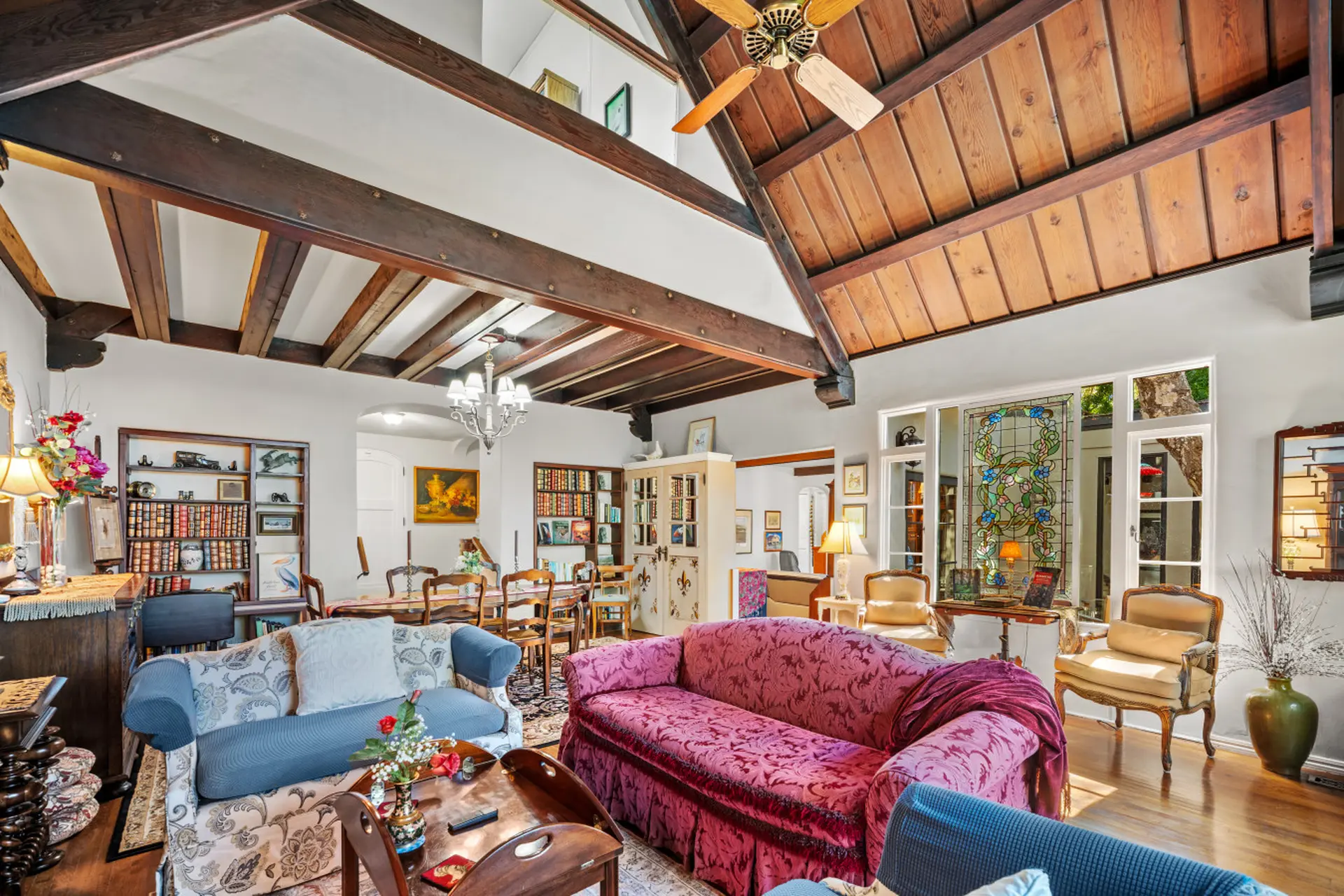 A living room with a vaulted, beamed ceiling, wood paneling, and stained-glass windows.