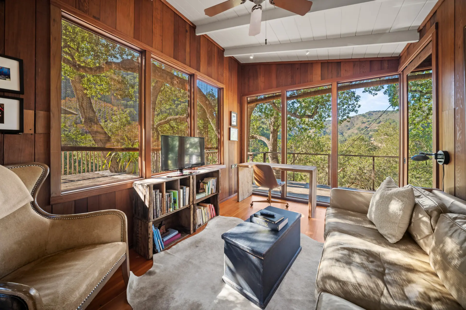 Cozy living room with wood paneling, large windows with nature views, and comfortable seating.