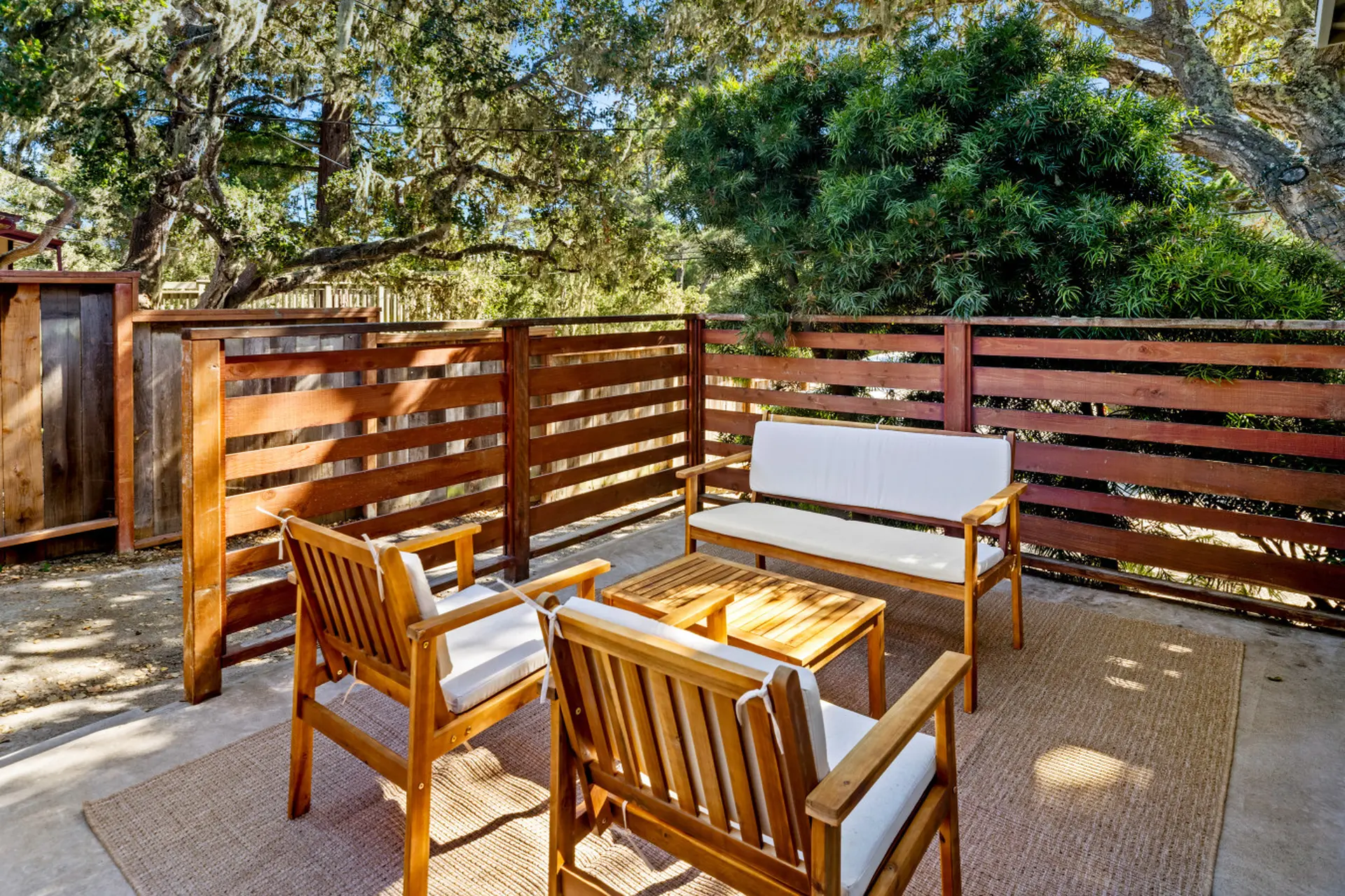 Outdoor seating area with wooden chairs, a bench, and a coffee table on a patio.