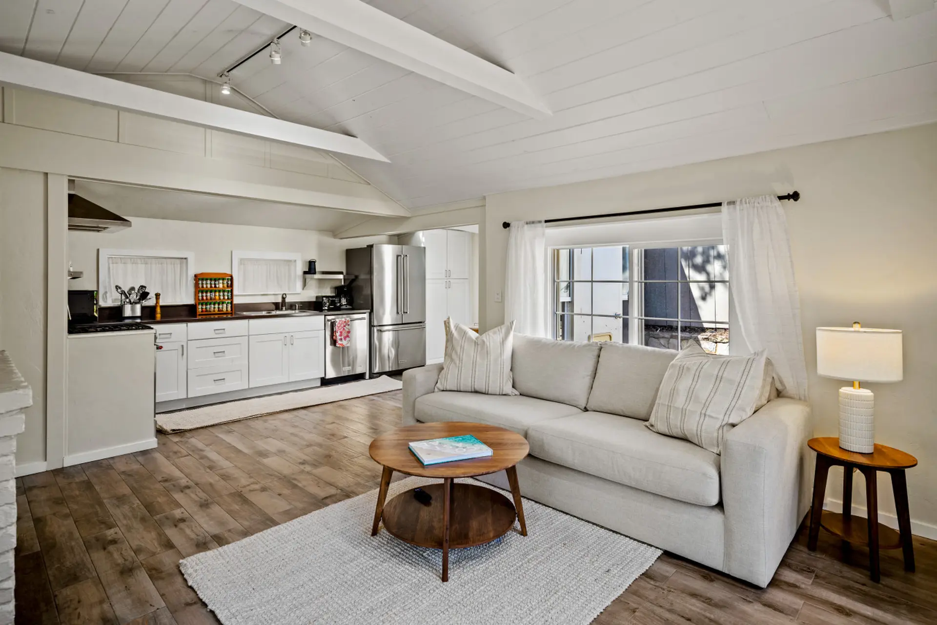 Living room with couch, coffee table, and kitchen area.