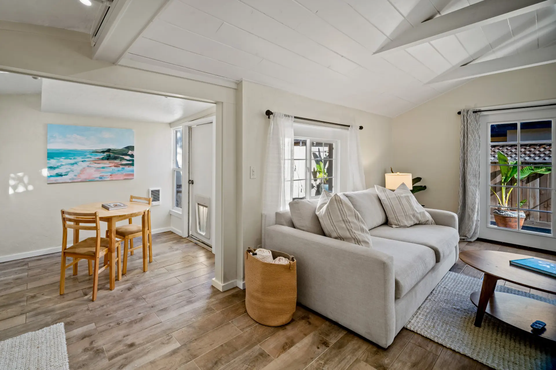 A bright and airy living room with a sectional sofa, coffee table, and dining area.